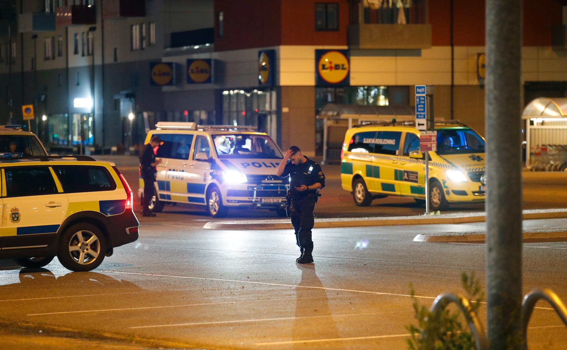 Poliser och ambulans i Flemingsbergs centrum, efter att en person hittats med misstänkta skottskador utomhus.