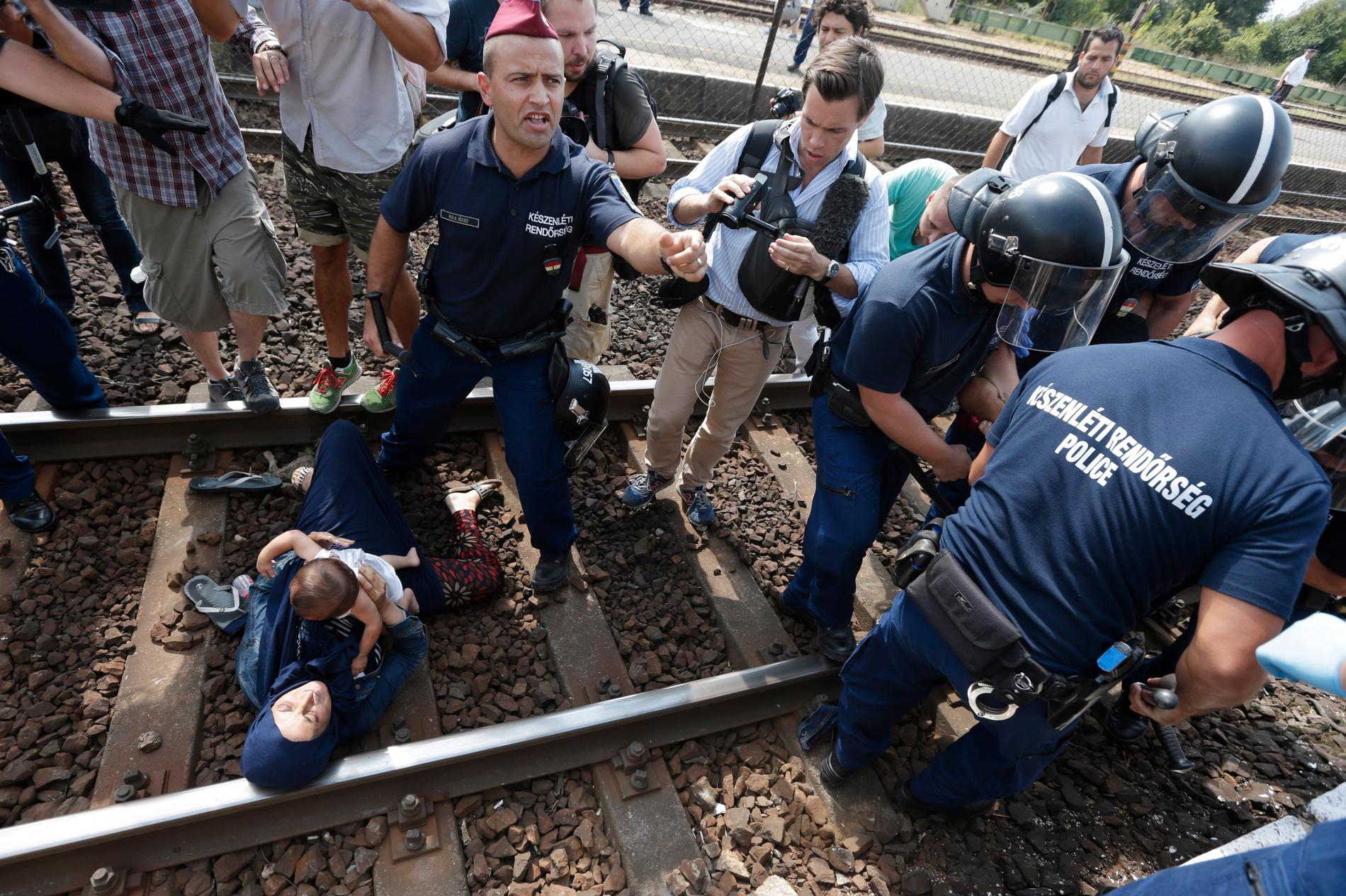 En flyktingfamilj försöker fly från polisen sedan de tvingats av tåget i den ungerska staden Bicske, knappt fyra mil väster om Budapest.