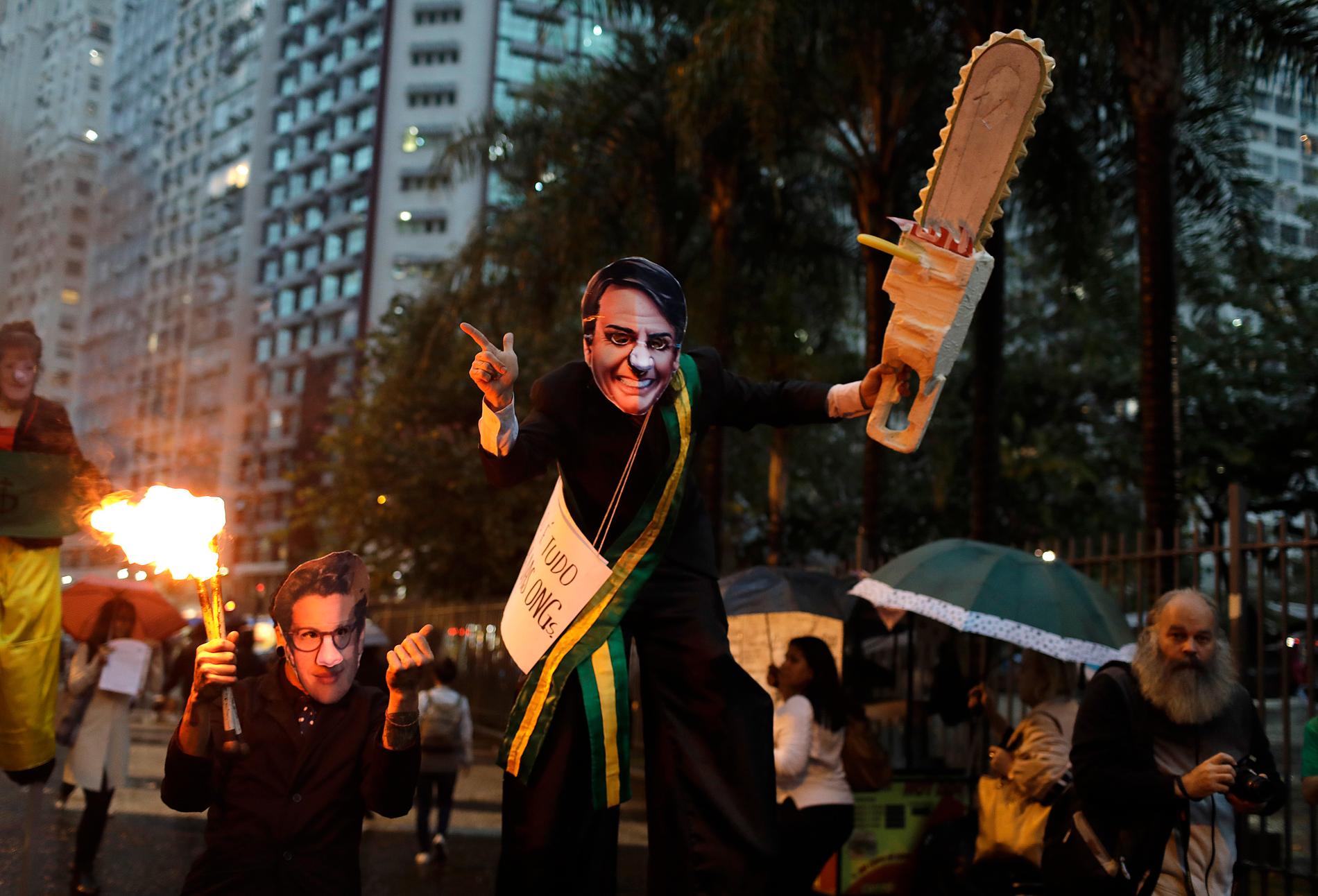 En demonstrant med Bolsonaro-mask och en låtsas-motorsåg protesterar i Rio de Janeiro till stöd för Amazonas.