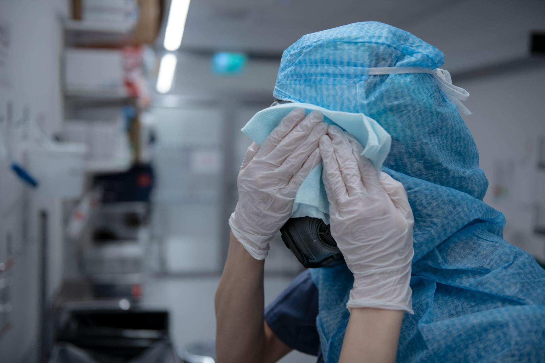 En sjuksköterska tvättar sin skyddsmask efter ett arbetspass på intensivvårdsavdelningen på Södertälje sjukhus under pandemins första år 2020.