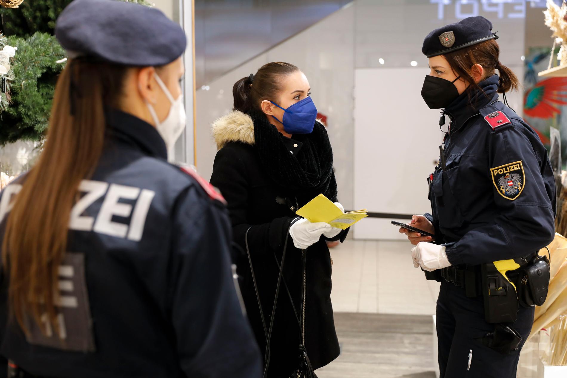 Poliser kontrollerar vaccinpass i ett köpcentrum i Wien den 12 januari.