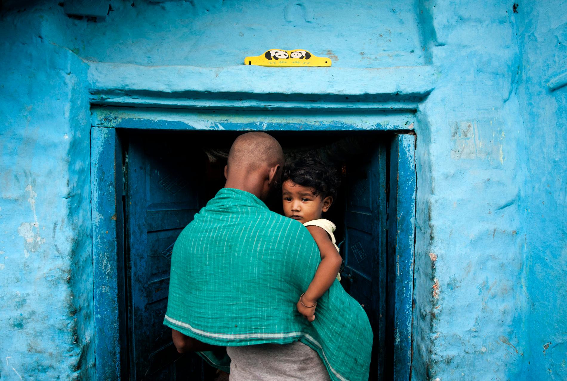 En man bär på ett barn i New Delhi, Indien. Dödligheten bland barn under fem år över hela världen har minskat kraftigt under de senaste två årtiondena.