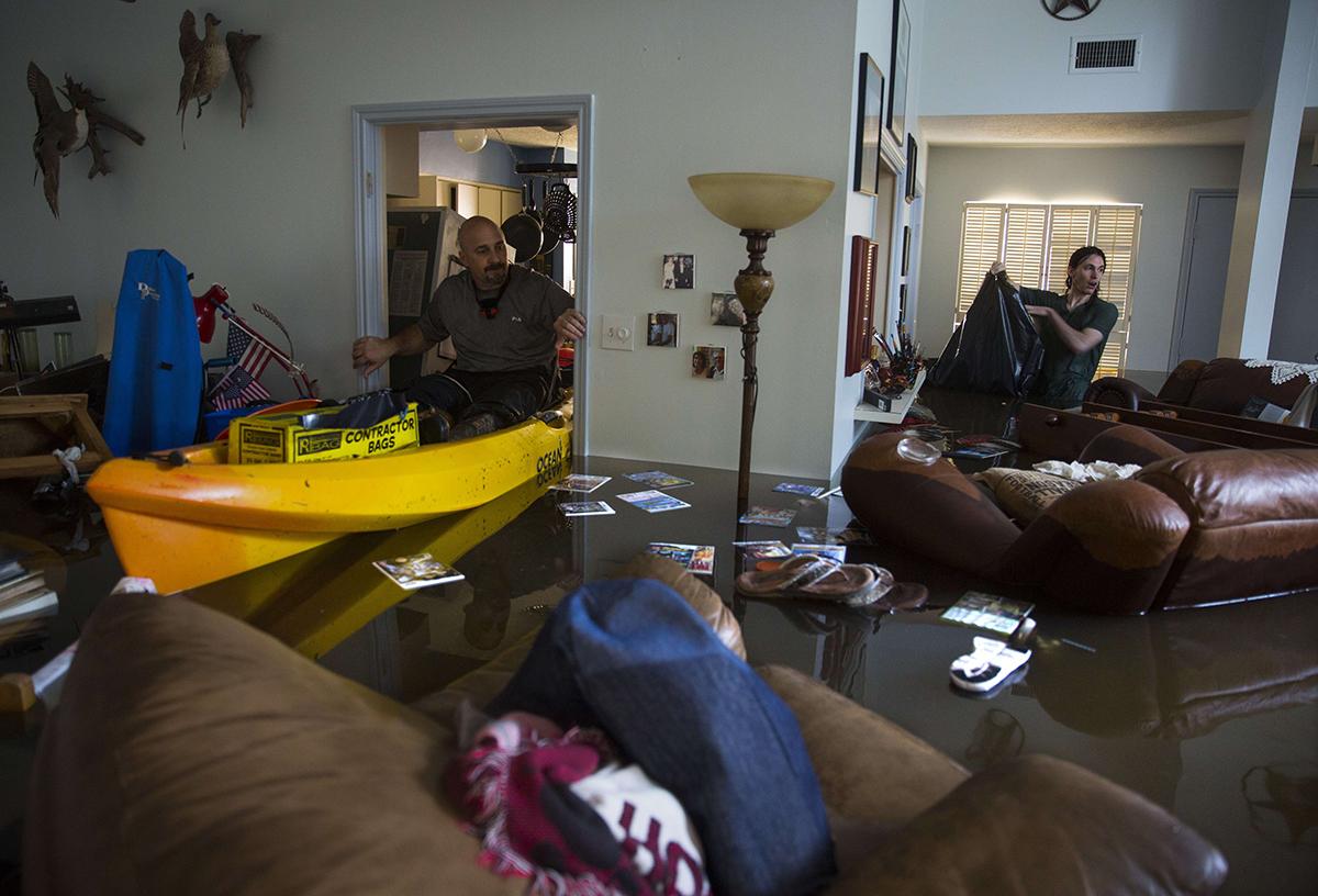 Larry Coser Jr och hans son Matthew försöker rädda värdesaker från Larrys fars hus efter att det svämmats över av vatten i Houston. 