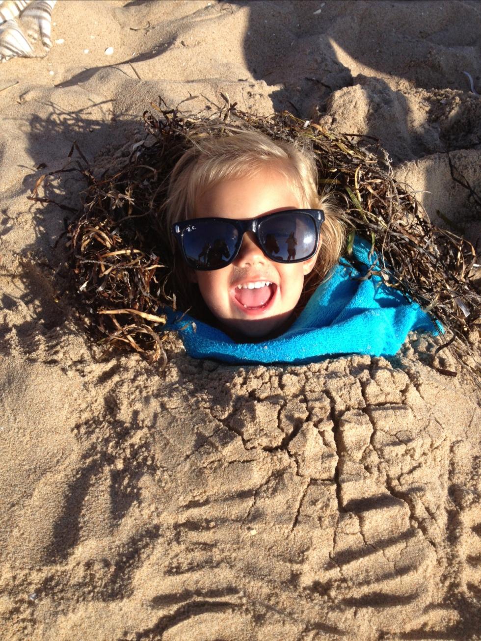 Moster gräver ner vår busiga dotter Nova, 2, i sanden en kväll på stranden, skriver Emma.