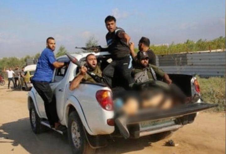 Skärmdump från den video där en kvinna syns ligga livlös på ett bilflak, omgiven av Hamas-män. När Shanis mamma fick se filmen kände hon igen sin dotters tatueringar. 