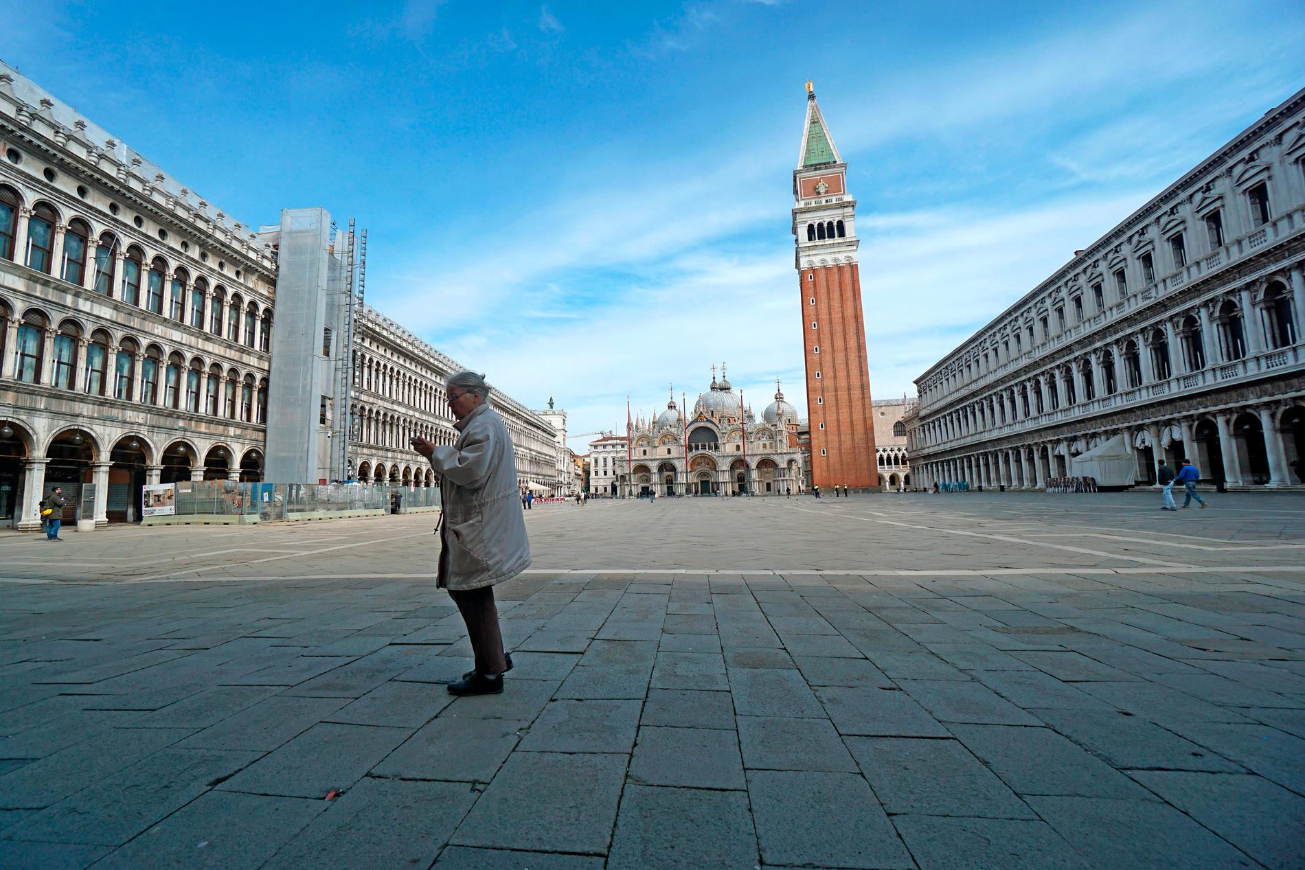 En kvinna går ensam över den spöklikt tomma Markusplatsen i Venedig. 
