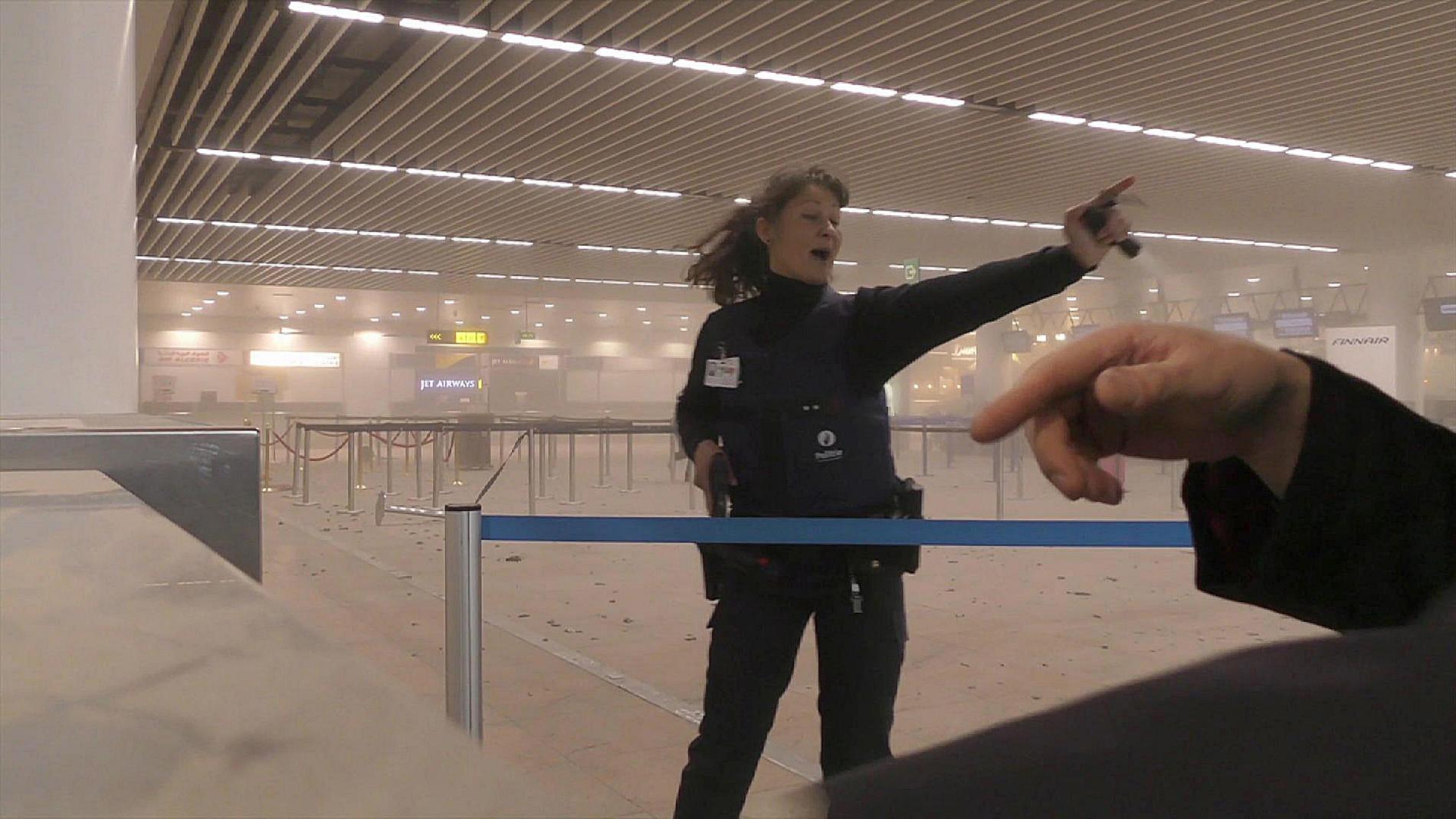 Polis med draget vapoen inne i en rökfylld flygplats i Bryssel