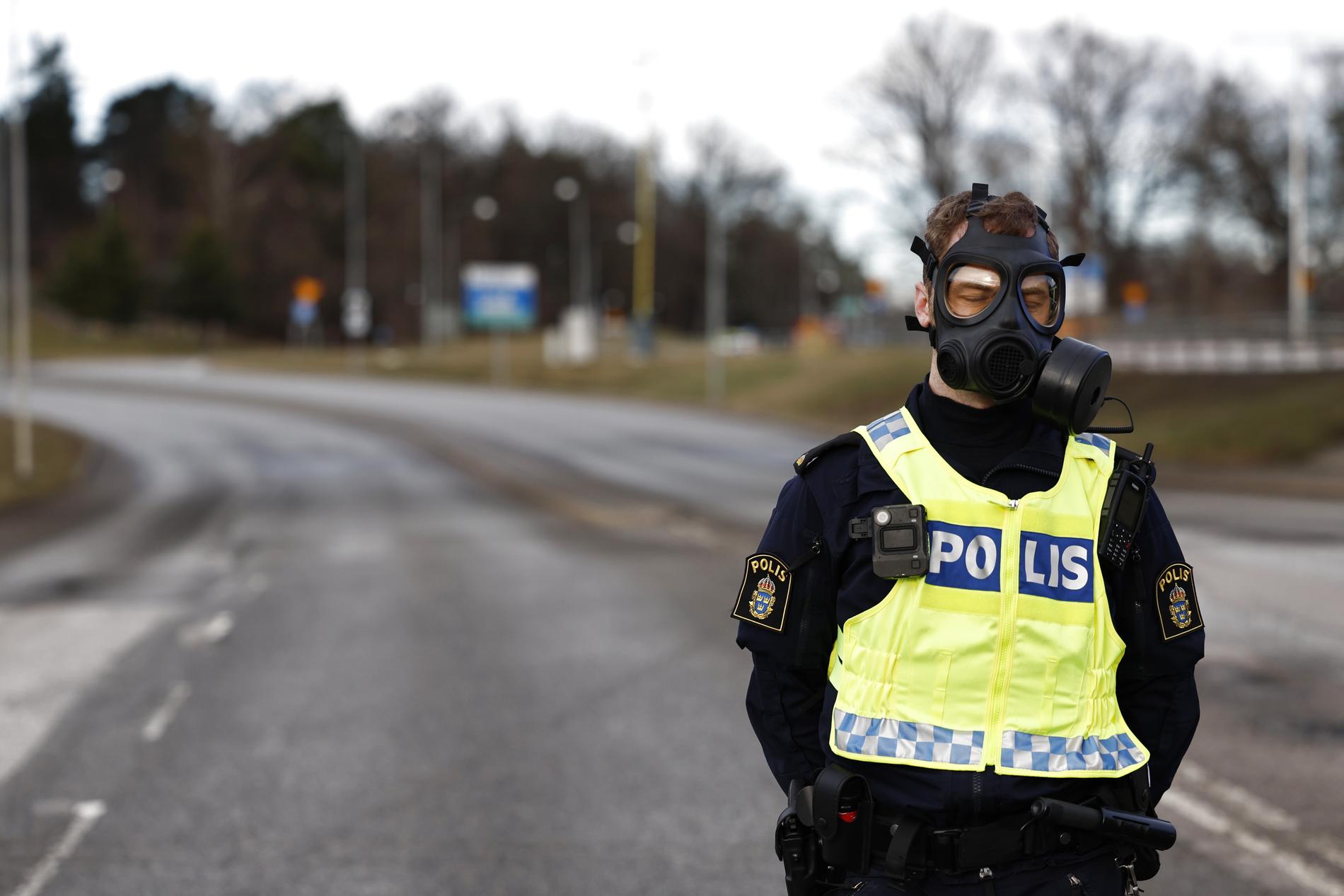 Polis i gasmask vid Säkerhetspolisens högkvarter i Solna norr om Stockholm under fredagen.