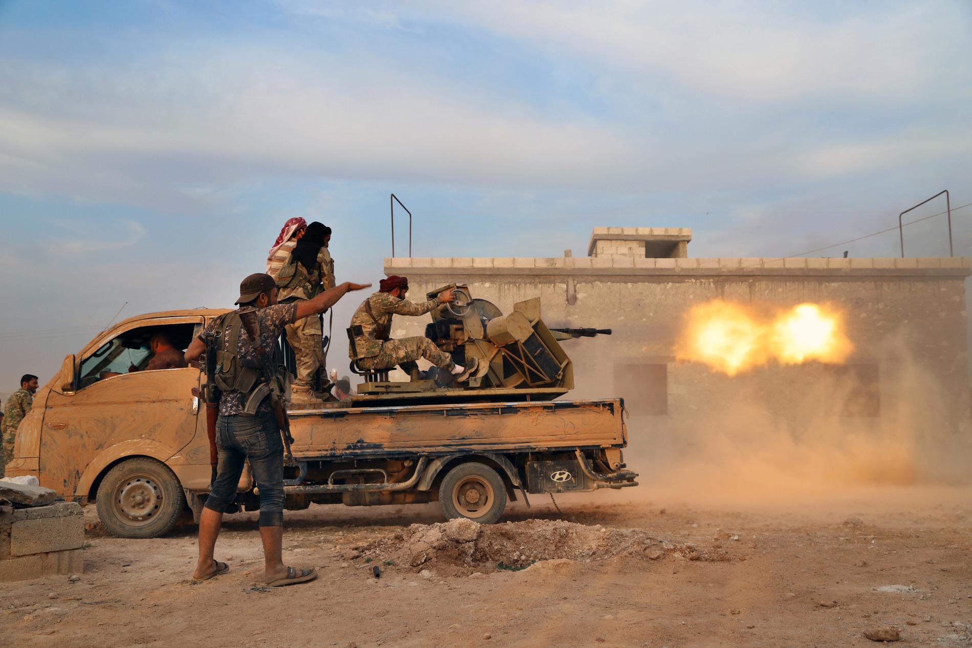 Turkietstödda syriska oppositionsstridande avfyrar ett tungt maskingevär mot kurdiska krigare i Manbij.