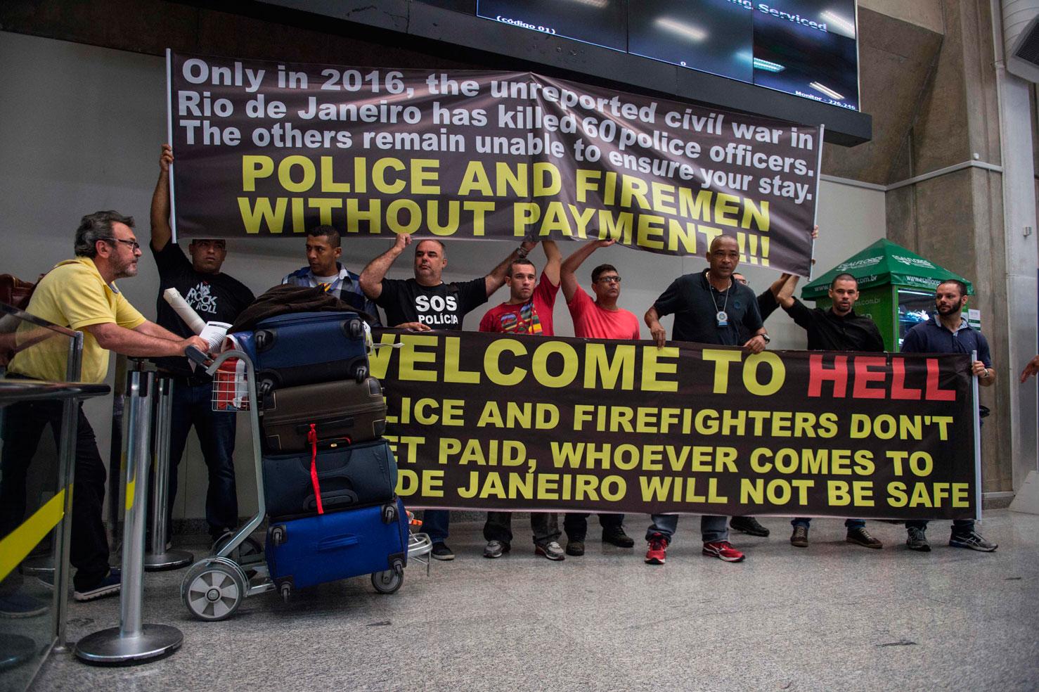 Polis  välkomnar anlända  på en flygplats i Rio med skylten ”Välkomna till helvetet”, när de demonsterar mot sina arbetsvillkor och försenade löner.