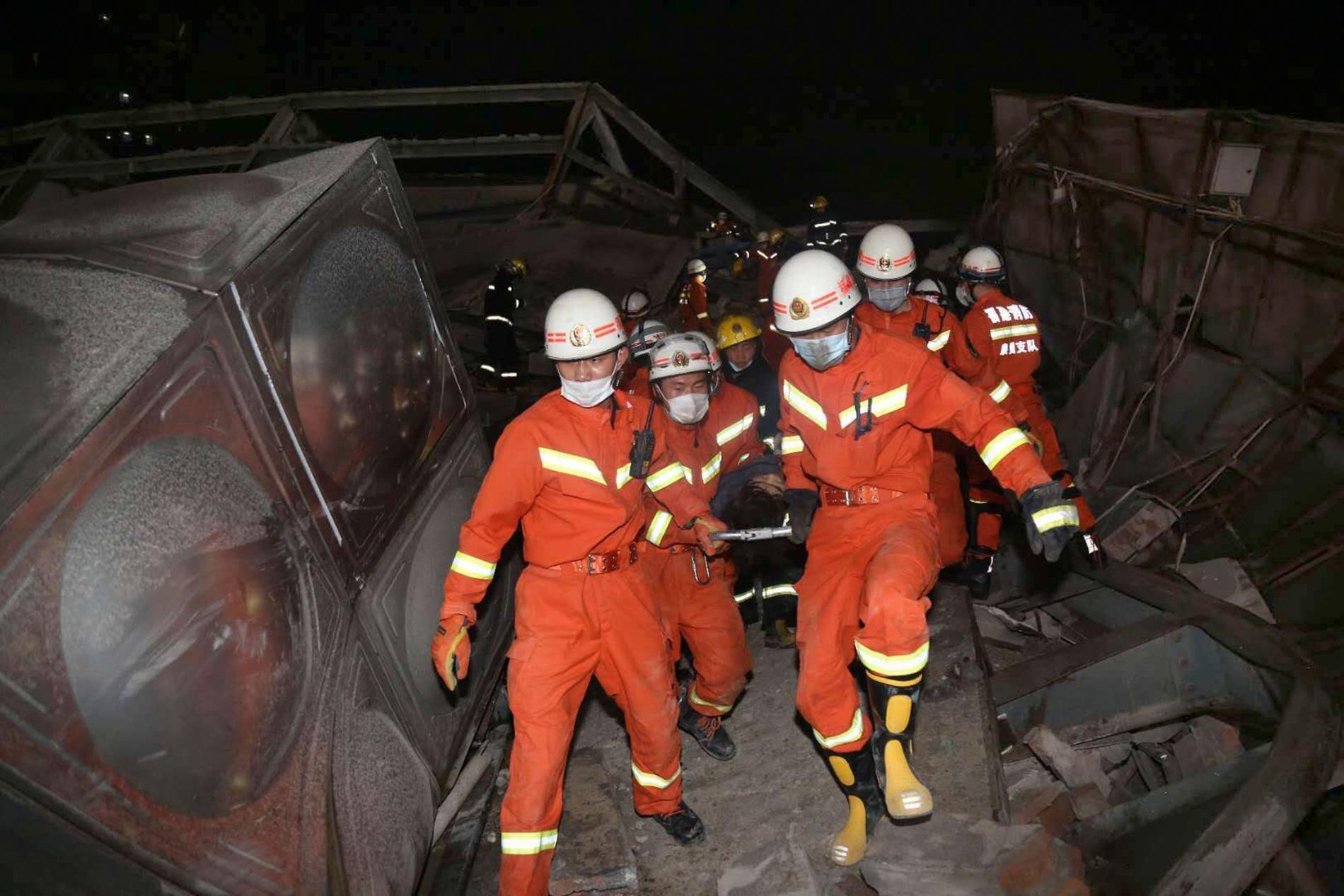 Räddningsarbetare bär ut en skadad person ur rasmassorna efter den kollapsade byggnaden i staden Quanzhou i Fujianprovinsen i Kina.