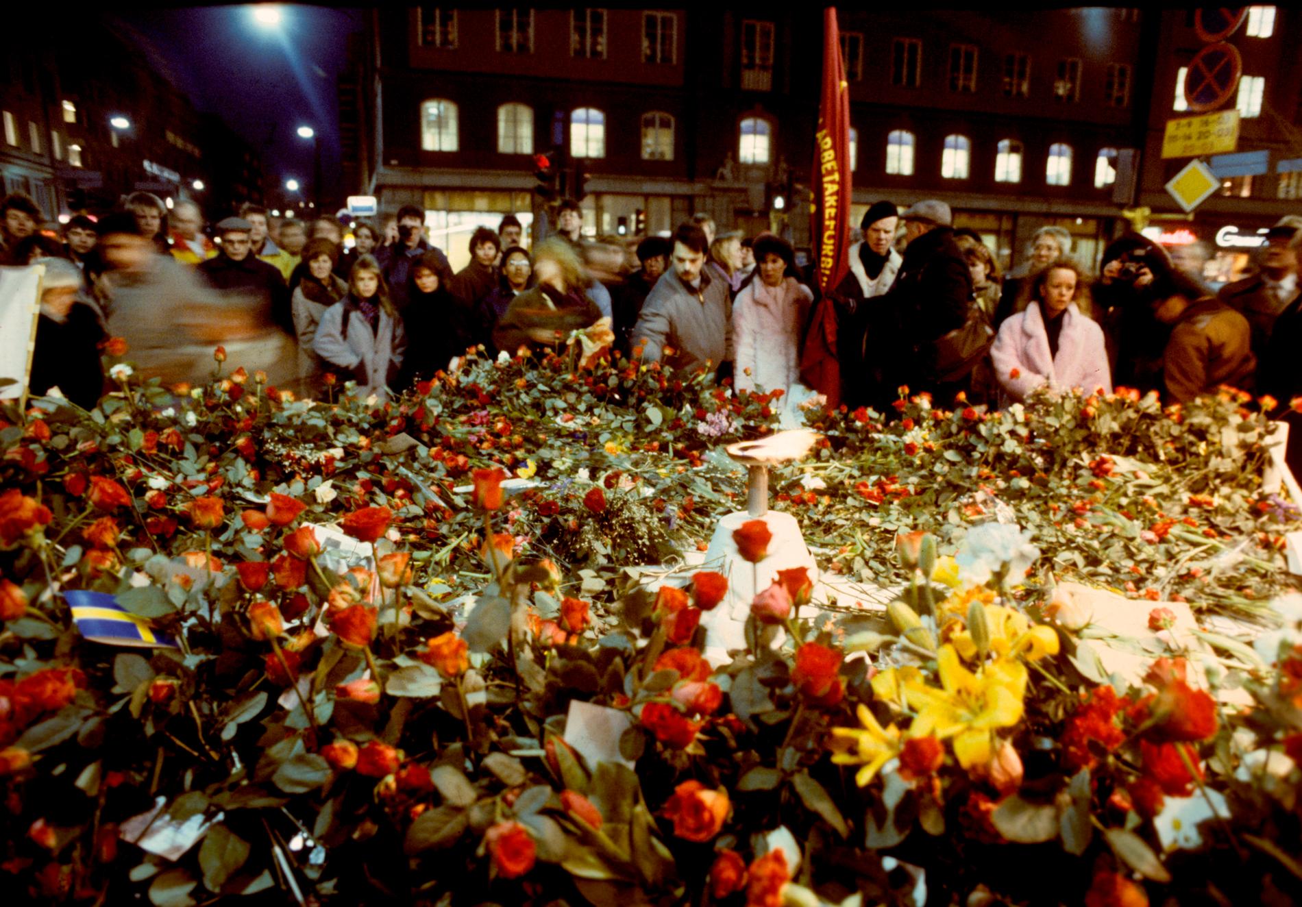 Sörjande människor lägger blommor på mordplatsen vid hörnet av Sveavägen och Tunnelgatan i Stockholm i mars 1986, för att hedra Sveriges statsminister Olof Palme som blev skjuten till döds på platsen. Arkivbild.