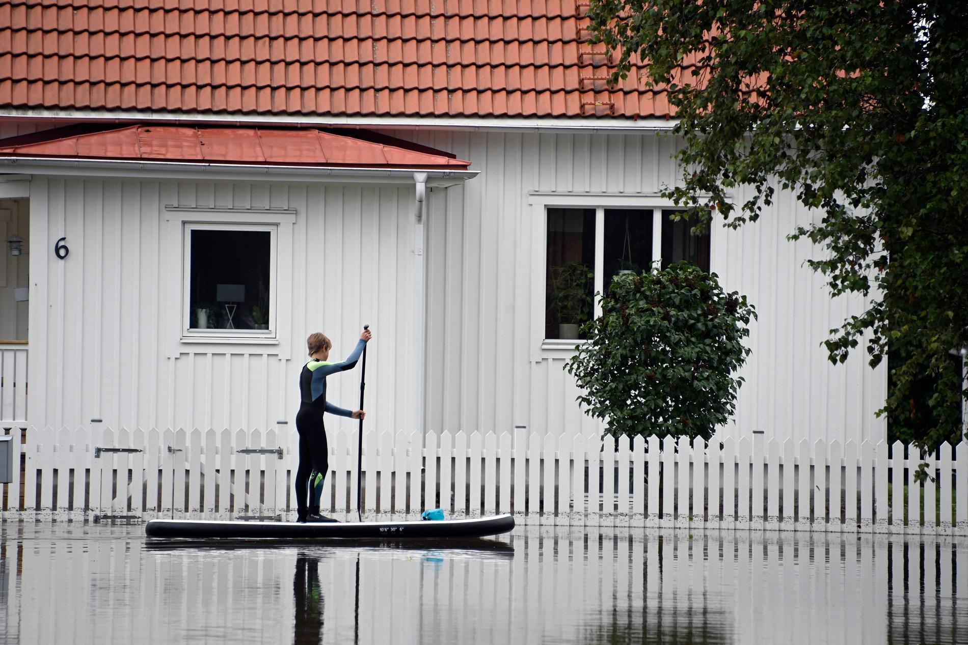 Stora översvämningar i Gävle. En person tar sig fram på en SUP-bräda.