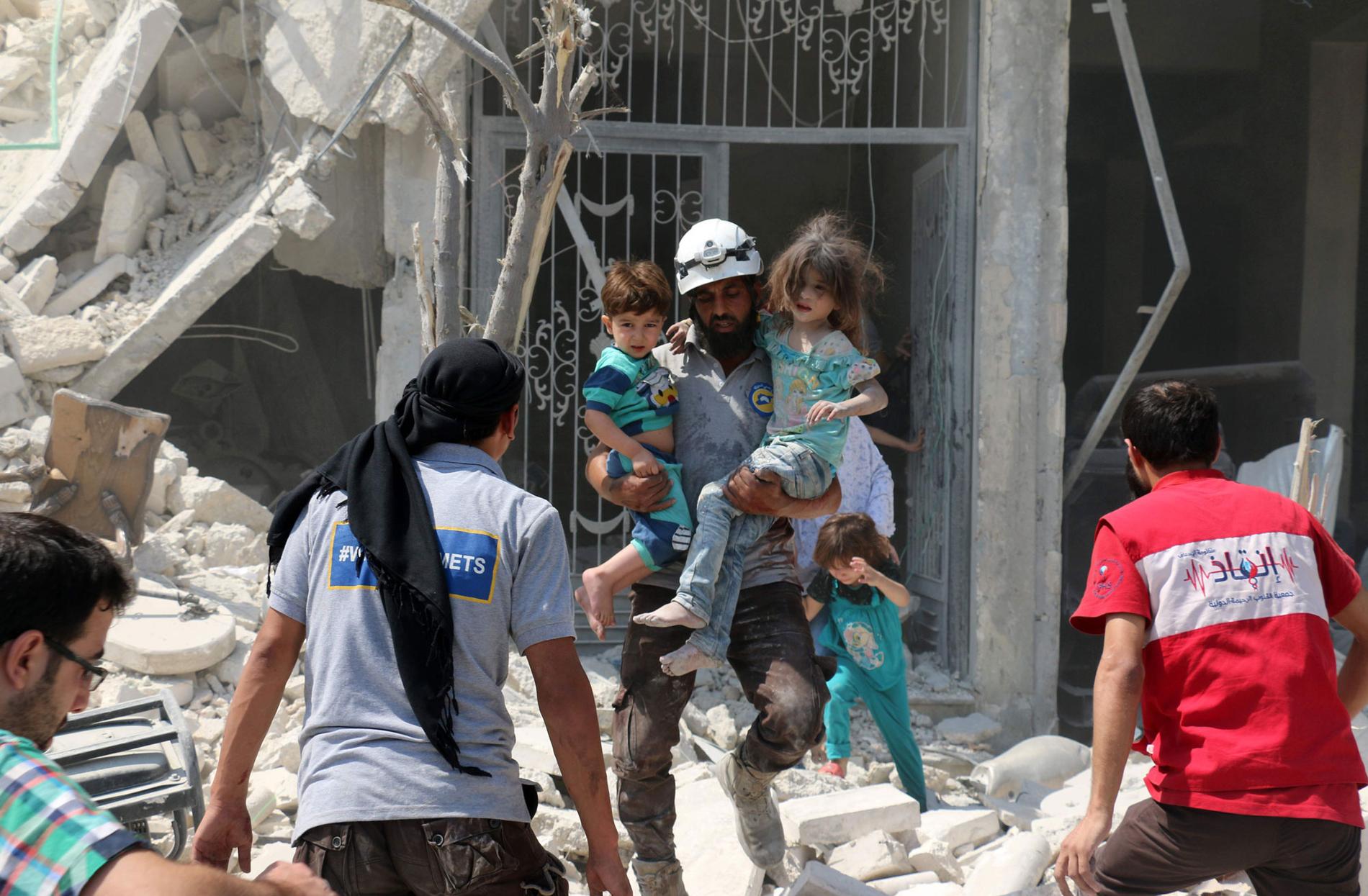 Räddningsarbetare bär ut barn som överlevde bombningar i Aleppo i lördags