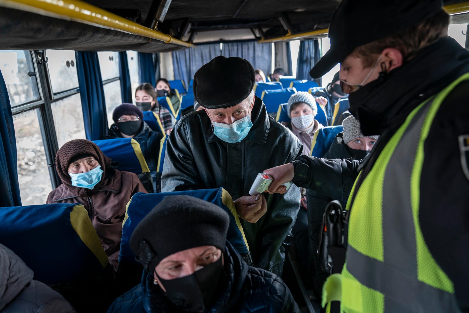 En polis mäter temperaturen på passagerare på bussen i närheten av i Ivano-Frankivsk i Ukraina. Arkivbild.