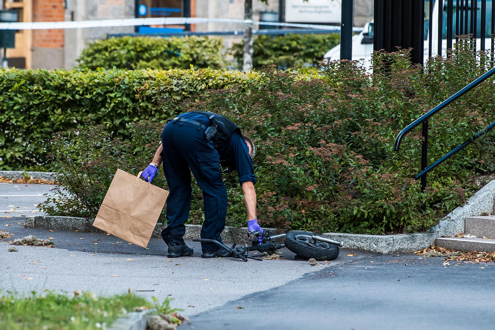 En polis plockar upp mopeddelar från gatan efter explosionen. 