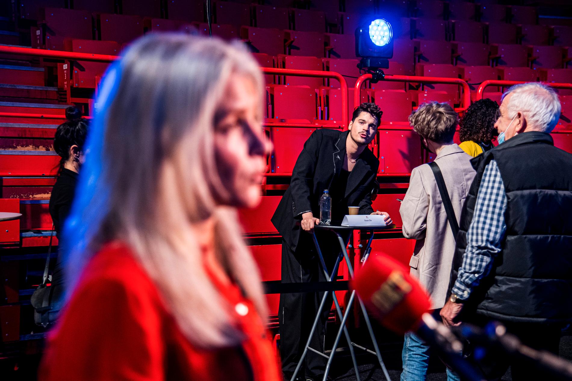 2022. Melodifestivalens app har precis havererat mitt under sändningen av den första deltävlingen. Mello-chefen Anette Brattström intervjuas i Aftonbladets direktsändning i förgrunden. Till programledaren Oscar Zia är det lång kö.