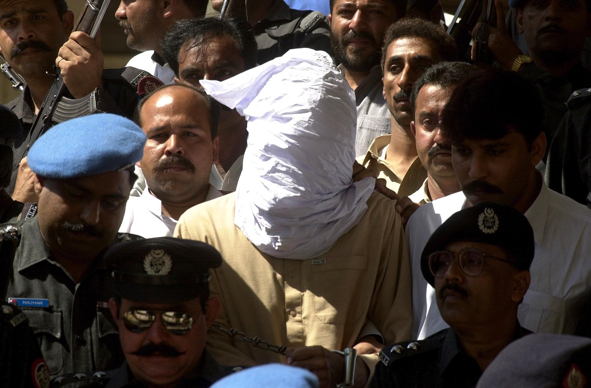 En person med täck ansikte, enligt polisens uppgifter Ahmed Omar Said som dömdes för mord på den amerikanske journalisten Daniel Pearl, förs in i rättegångssalen i Karachi i Pakistan 26 februari 2002.