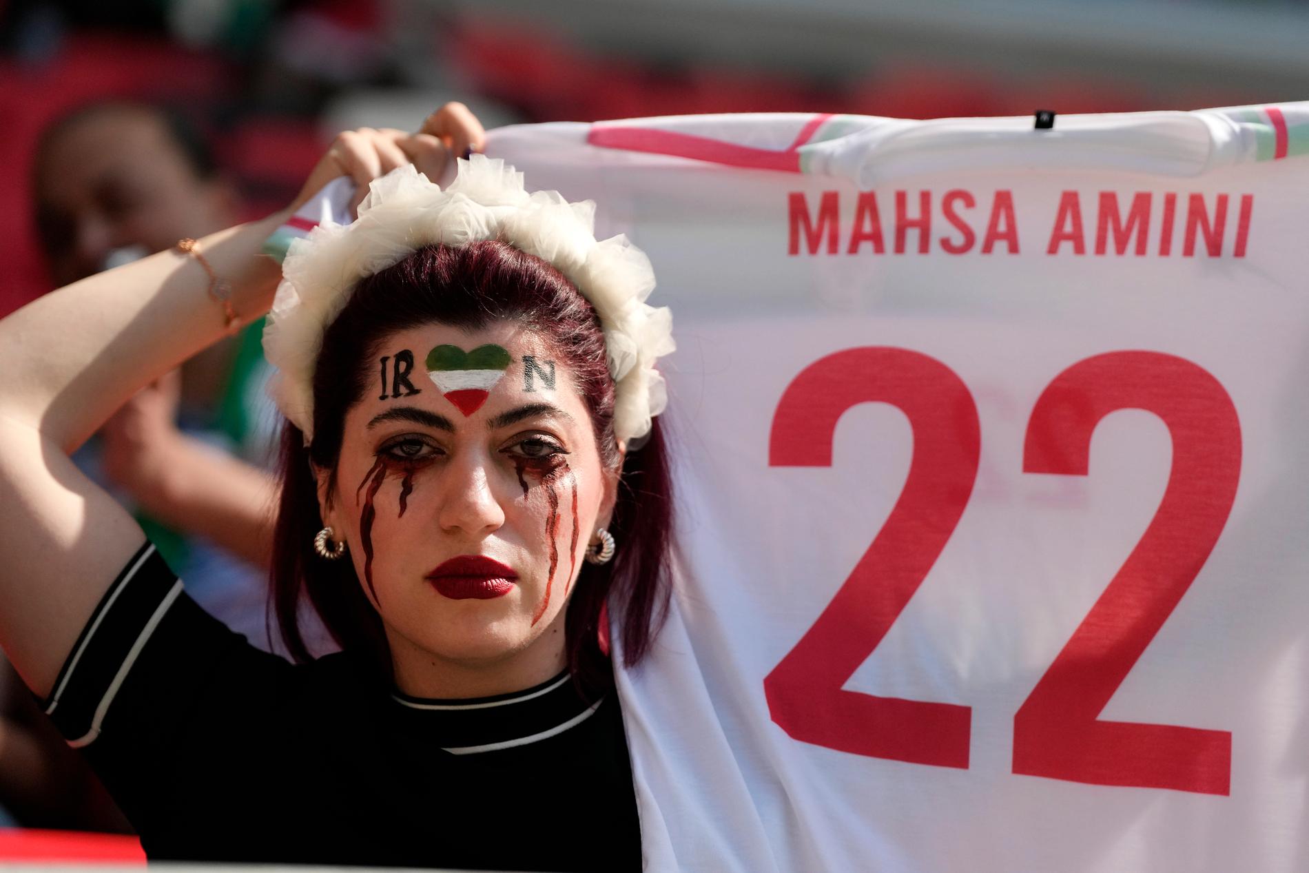 En kvinna håller upp en tröja till minne av 22-åriga Mahsa Zhina Amini.