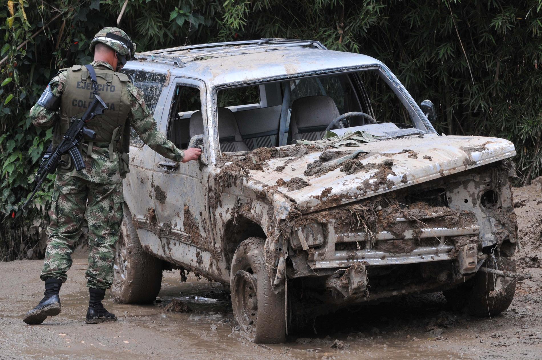 En soldat undersöker en bil som skadats i ett jordskred i Colombia 2011.