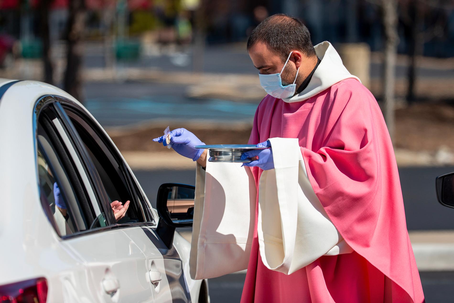 MOOSIC, USA Prästen William Mentz delar ut nattvarden till församlingsmedlemmar som sitter kvar i sina bilar i Moosic, Pennsylvania, på söndagen.
