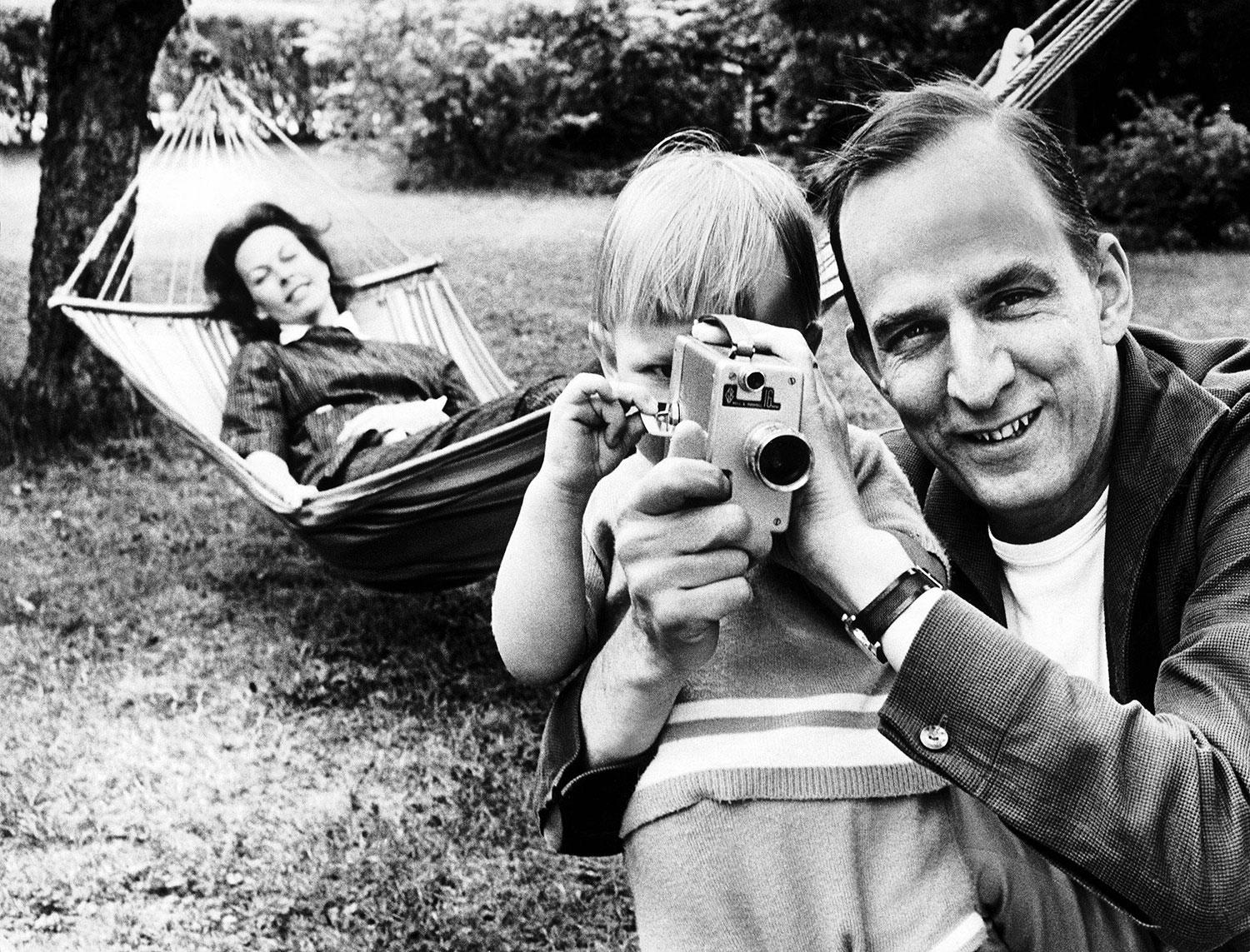 Regissören Ingmar Bergman lär sonen Daniel hur man använder en kamera. Käbi Laretai ligger i hängmattan i bakgrunden.