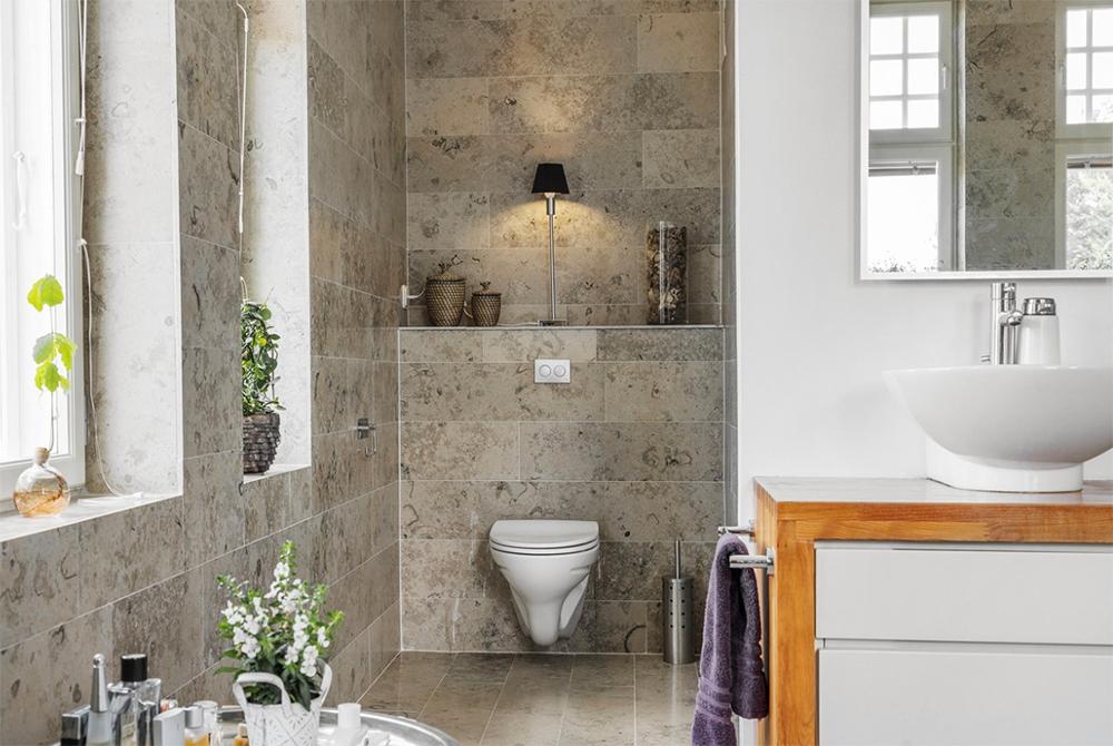 Badrum utrustat med inmurat badkar, dusch, handdukstork och vägghängd WC.