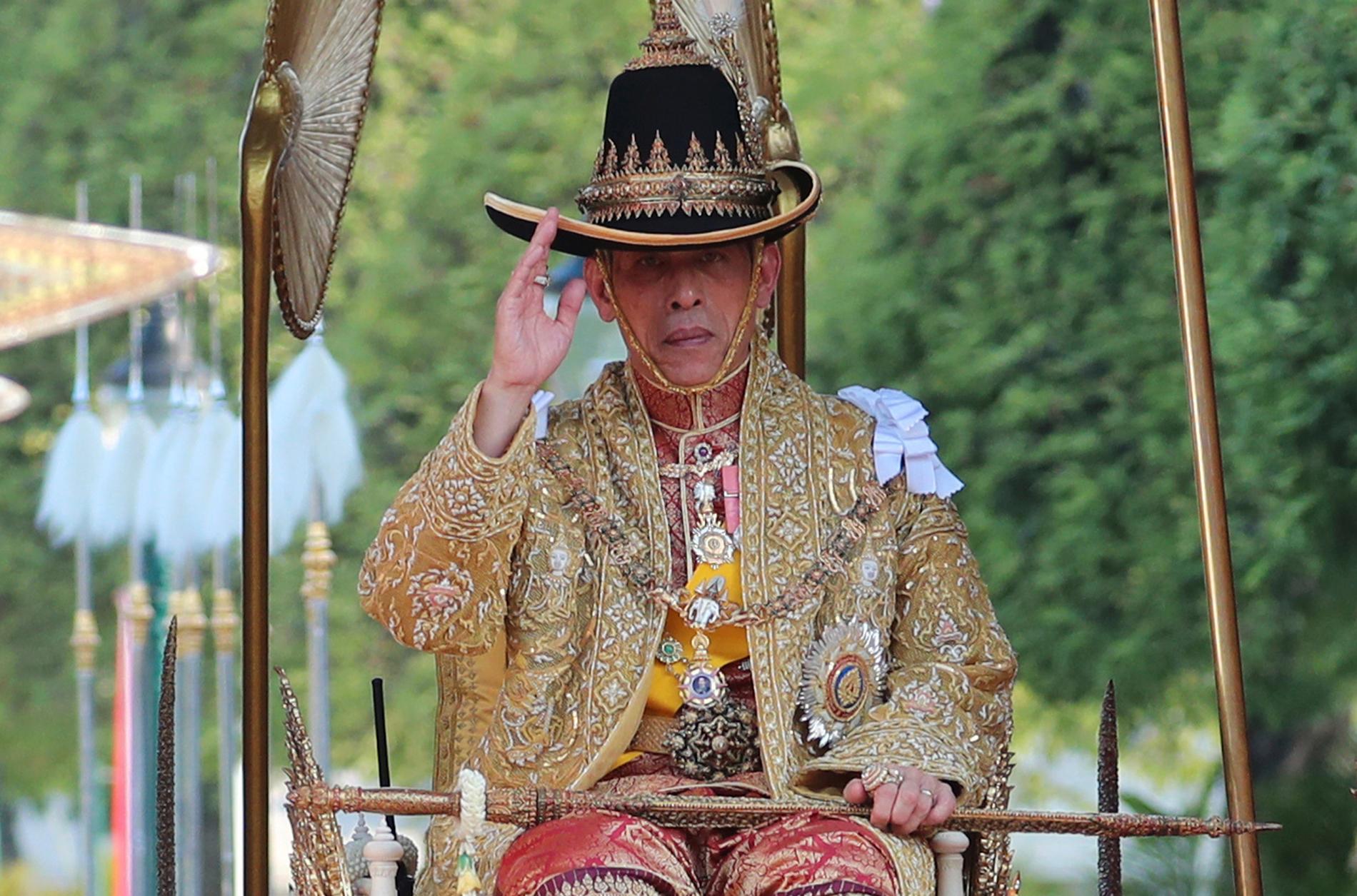 Kung Rama X bar en bredbrättad hatt med en fjäder under processionen.