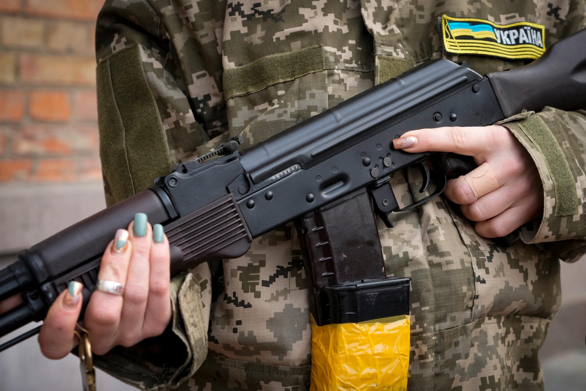 En civilförsvarskvinna håller i en kalasnikov under patrullering i Kiev på söndagen. 