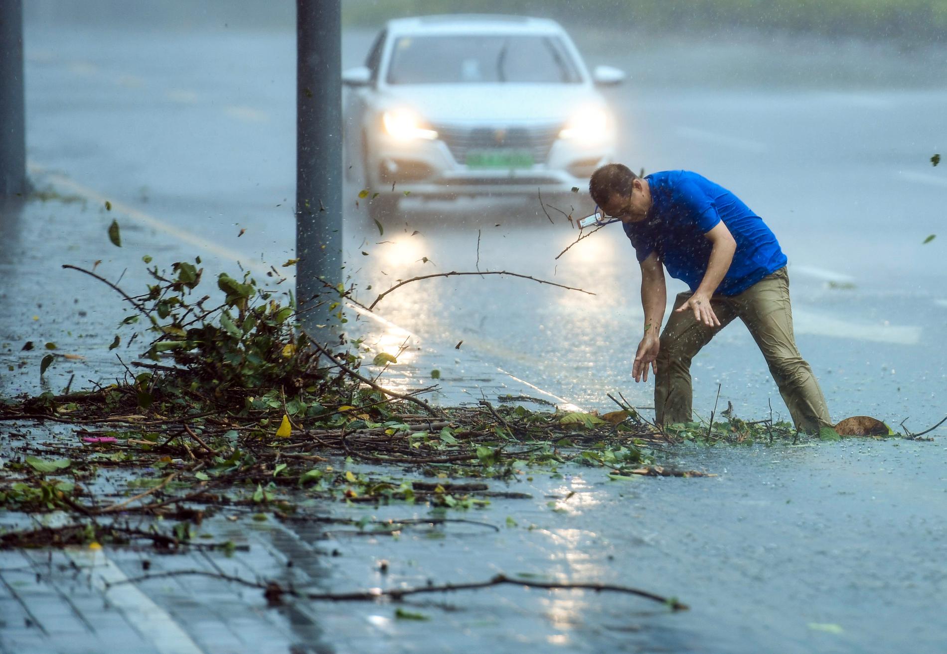 En man försöker forsla bort grenar som täpper till en brunn i staden Shenzhen i provinsen Guangdong i Kina.