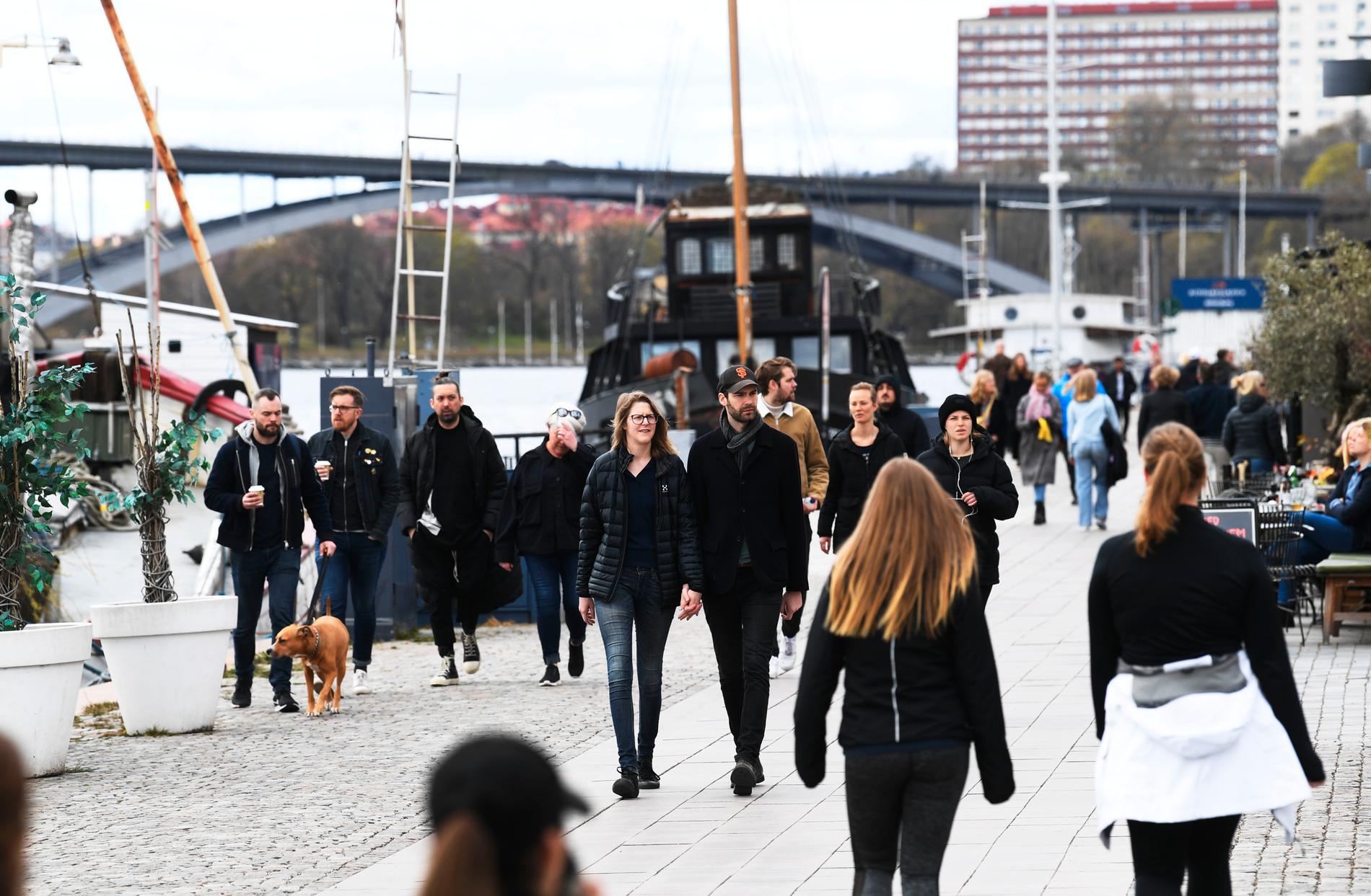 Personer flanerar på Norr Mälarstrand i Stockholm under en söndag i slutet av april.