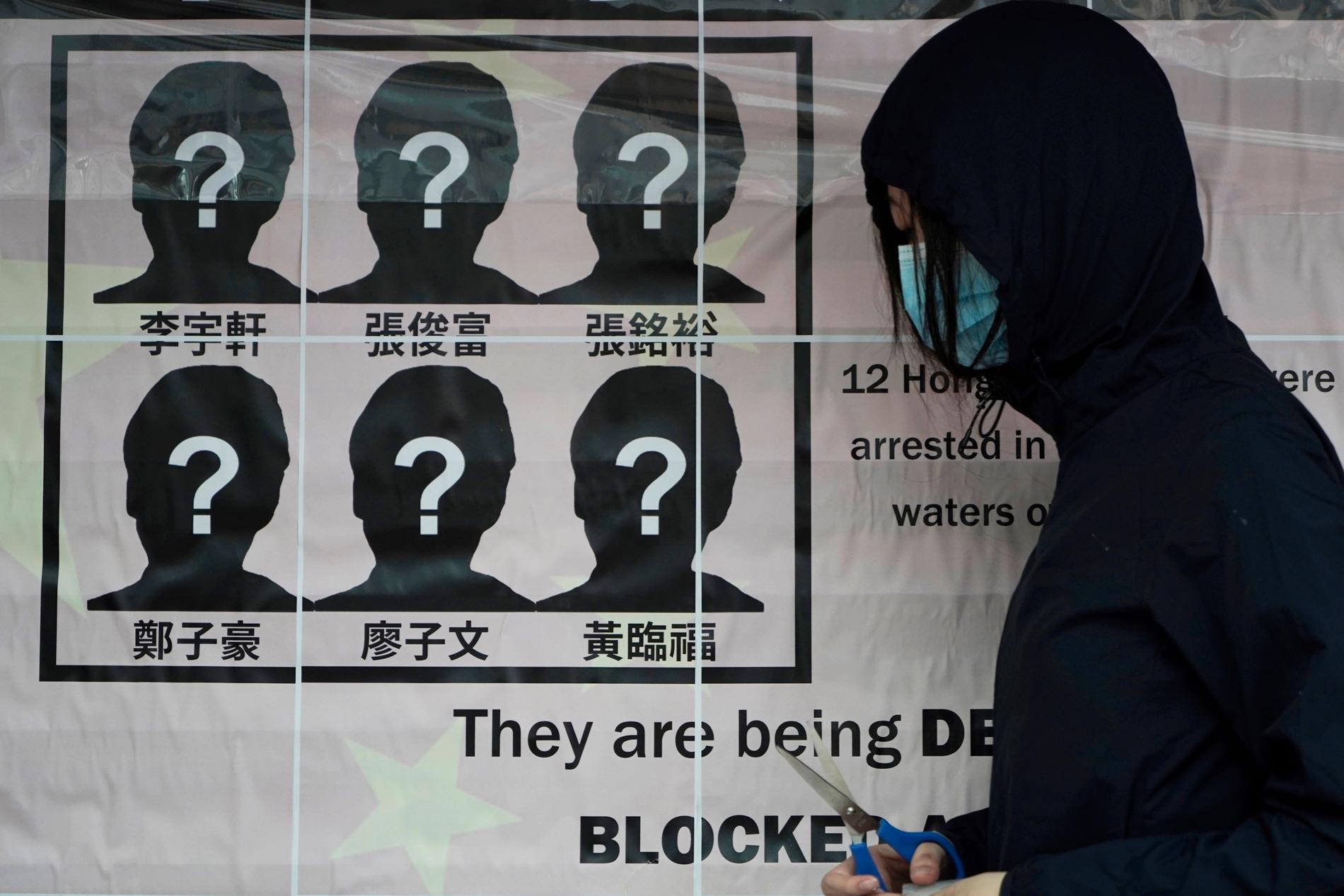 En universitetsstudent sätter upp en affisch som kräver att tolv aktivister som försökt fly från Hongkong släpps av Kinas myndigheter.
