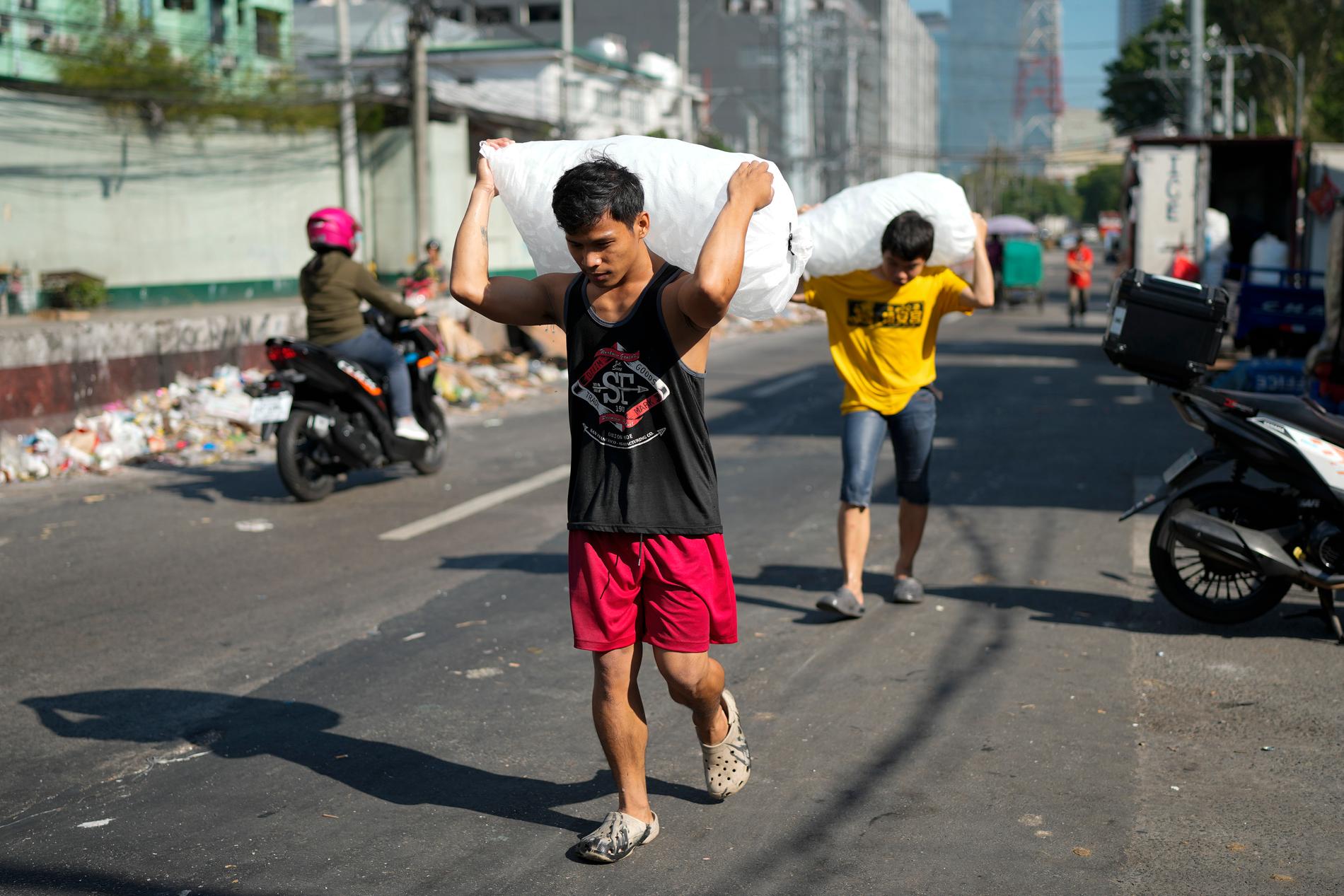 Män levererar säckar med iskuber under värmeböljan i Quezon City i Filippinerna.