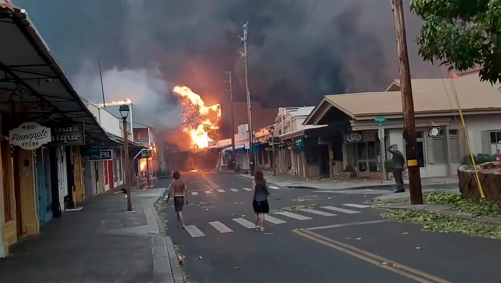Människor tittar på när rök och lågor fyller luften från rasande skogsbränder på Front Street i centrala Lahaina, Maui tisdagen den 8 augusti 2023.