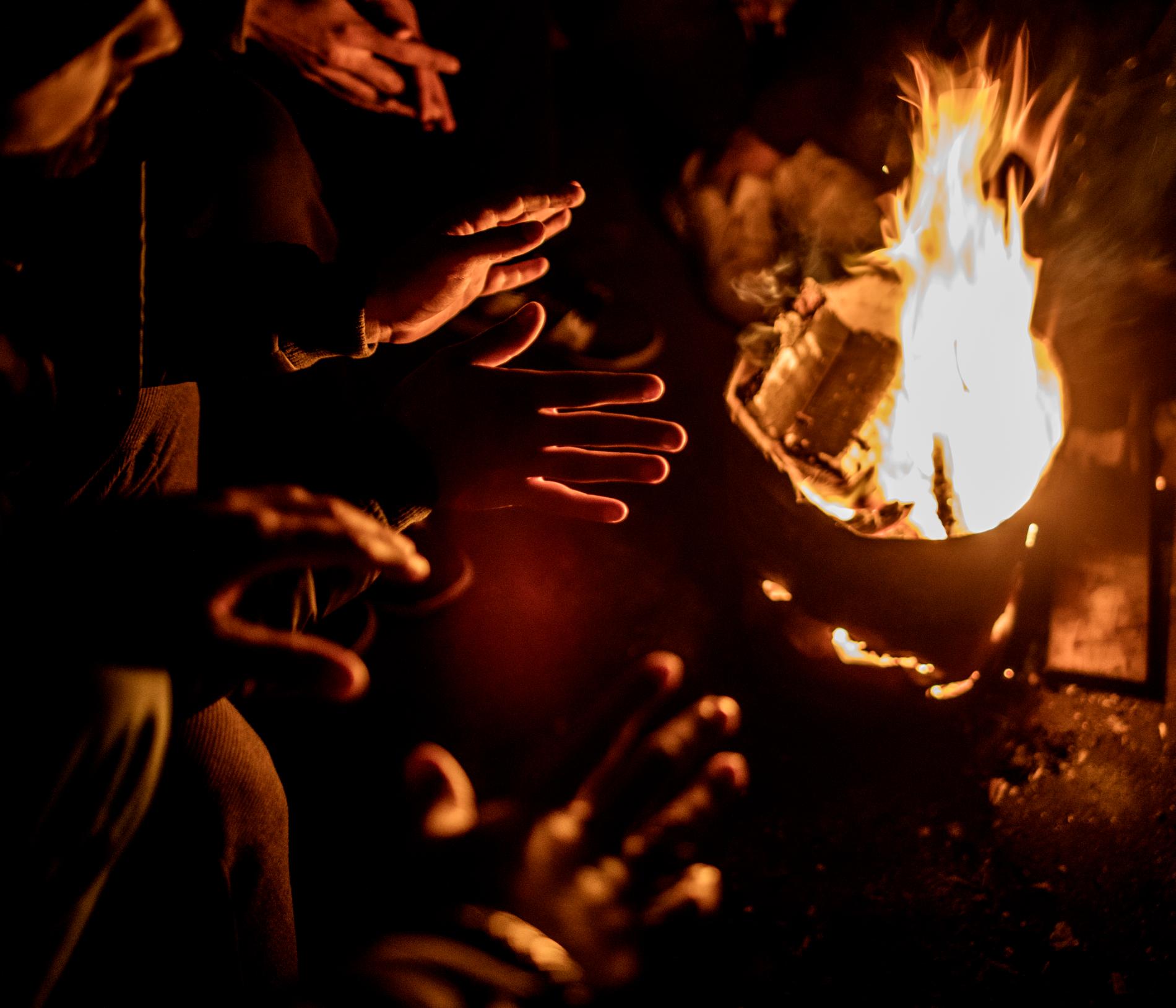 I den mörka lokalen finns ingen el och migranterna gör upp eld för att hålla värmen
