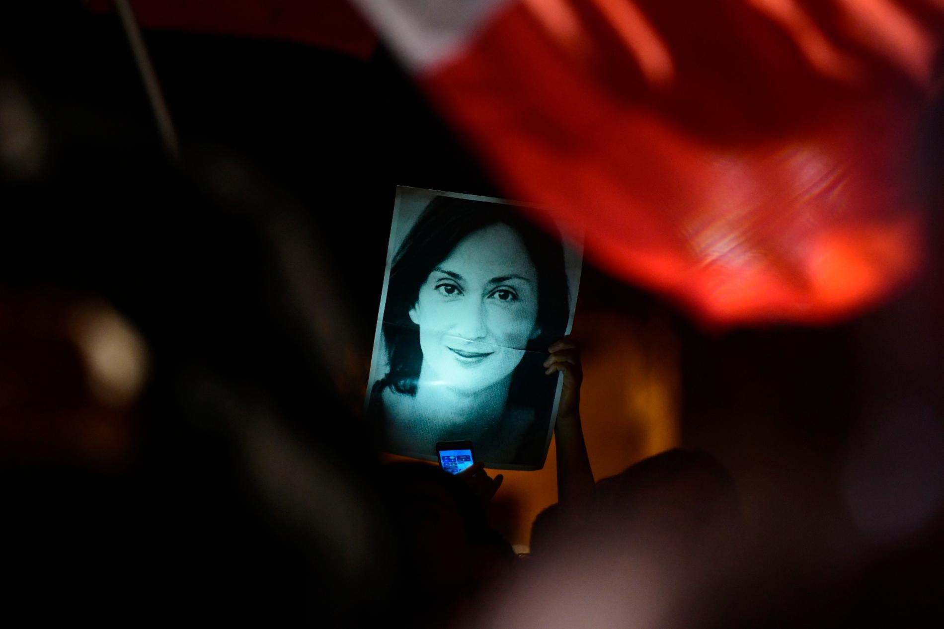 En demonstrant håller upp en bild på den mördare reportern Daphne Caruana Galizia vid en demonstration 2019.