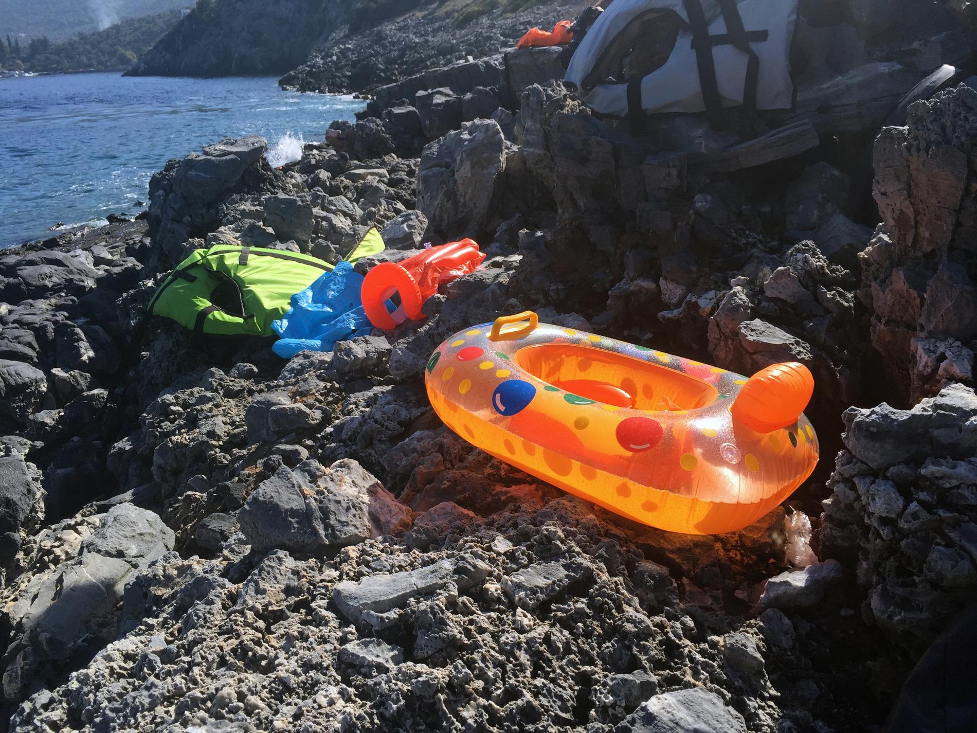 Falsk säkerhet. Enkla flytleksaker med varningstexten kvar och billiga uppblåsbara barnflytvästar på den klippiga stranden vid Samos norra kust.