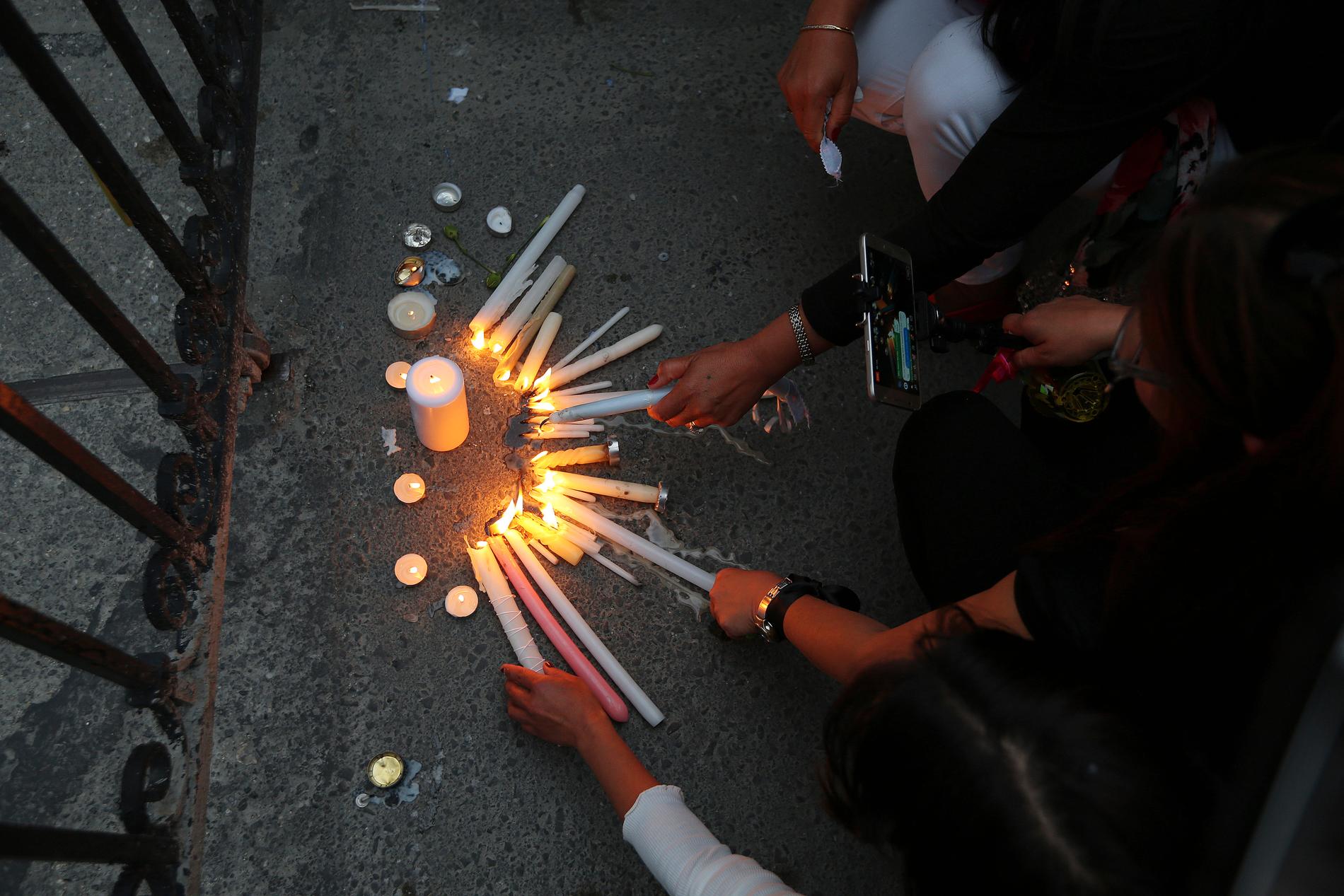 Kvinnor tänder ljus till minne av mördarens offer utanför presidentpalatset. 