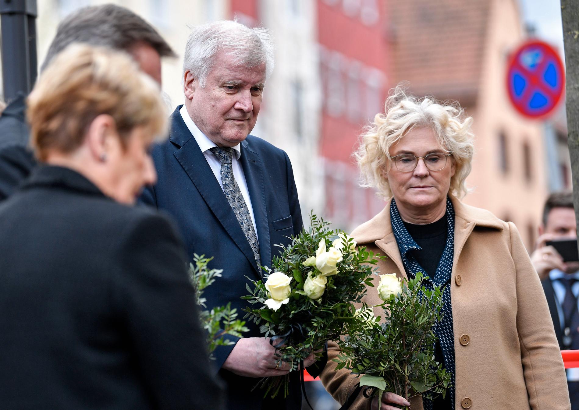 Tysklands inrikesminister Horst Seehofer, i mitten, och justitieminister Christine Lambrecht, till höger, lägger ner blommor utanför ett av de kaféer där flera människor dödades i onsdags.