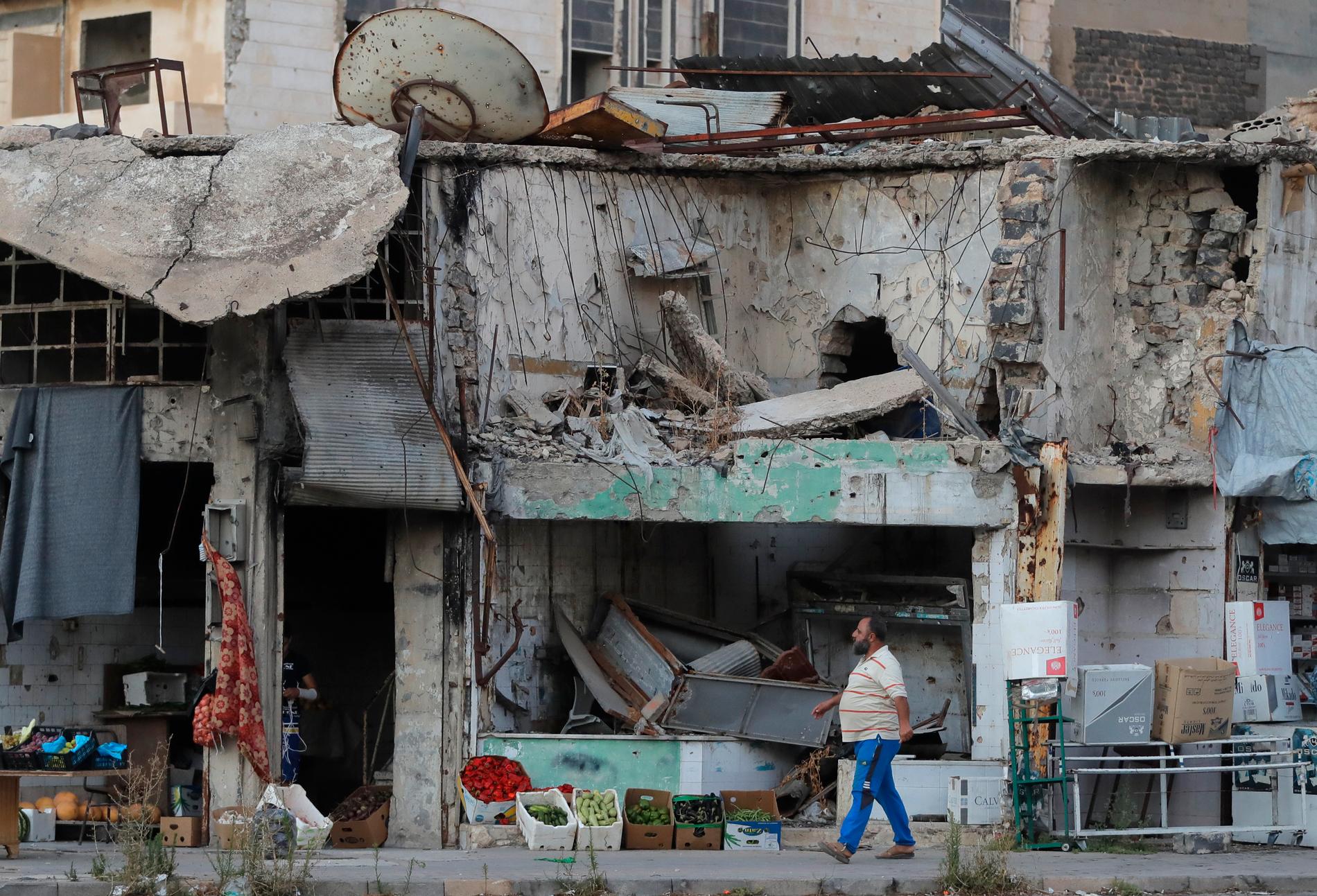 En man promenerar framför ett förstört hus i den syriska staden Homs. Stora delar av landets infrastruktur har sargats av kriget. Arkivbild.
