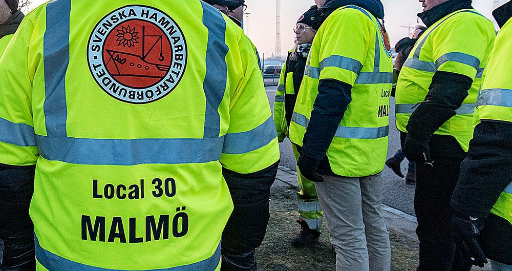 Strejkvakter från Hamnarbetarförbundet utanför Norra hamnen i Malmö förra veckan. ”Hamnkonflikten är ett led i en långvarig kampanj för att inskränka möjligheterna för arbetare och tjänstemän att freda sig”, skriver Mikael Nyberg.