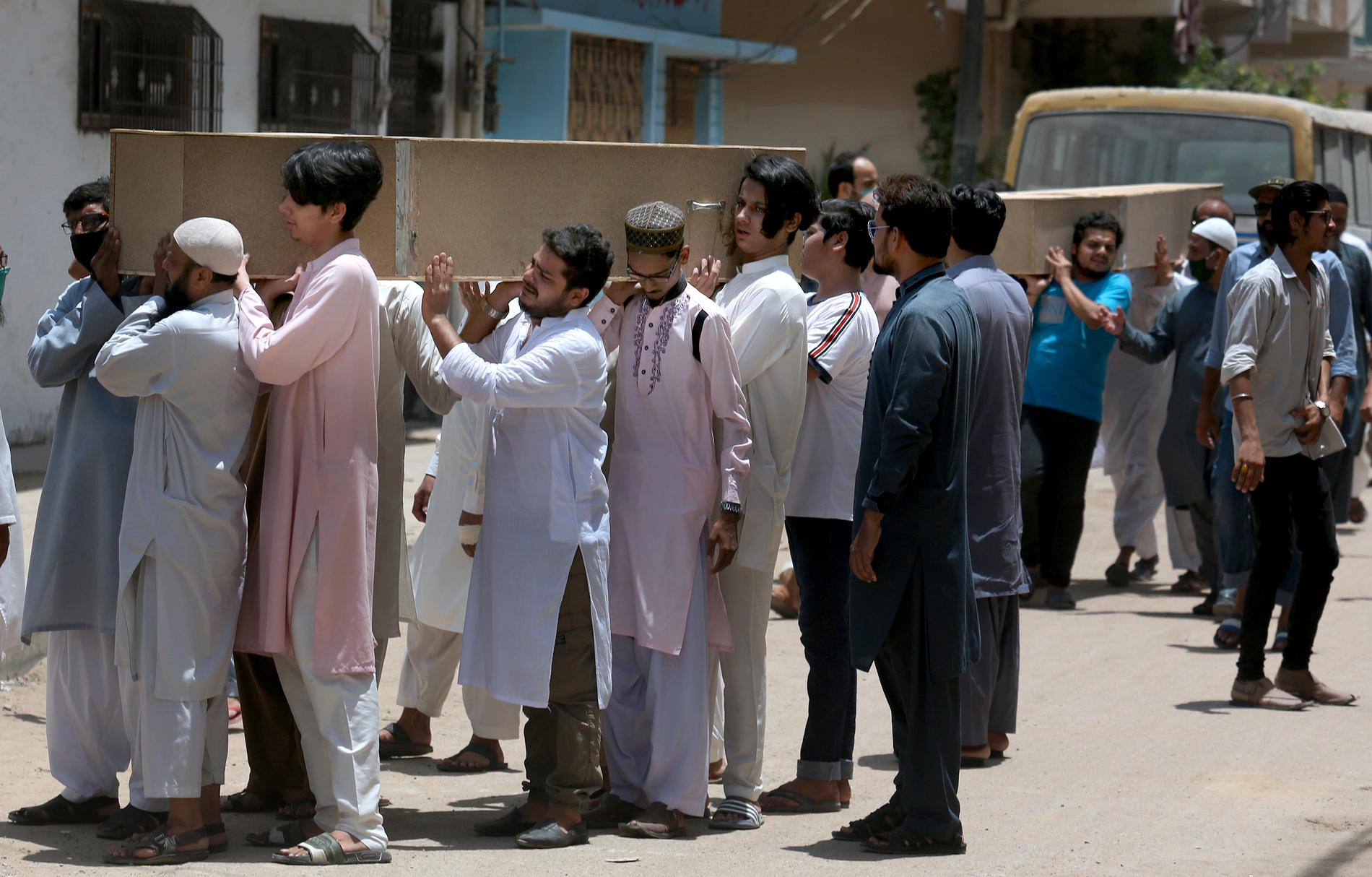 Människor bär kistor med offer från flygkraschen i Karachi.