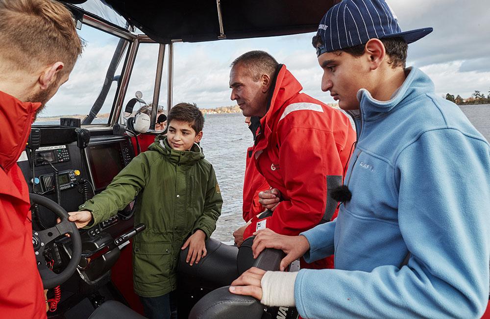 Nils Ingull visar 11-årige Abdulla och hans bror Mahmoud sjöräddningsbåten som ligger i Helgasjön, Växjö. Den är mindre än den båt som de blev upplockade med en kall natt i november 2015. Men det väcker ändå minnen att träffa sjöräddarna och att vara vid havet.
