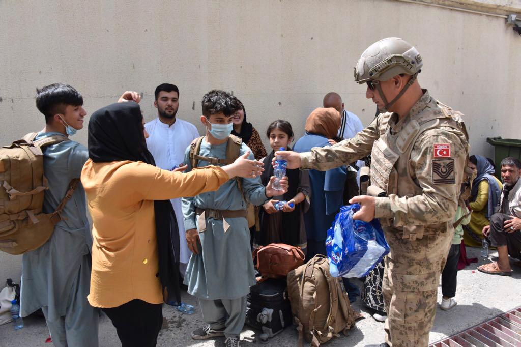 Turkisk militär delar ut vatten till turkiska medborgare som ska flygas hem från Kabul. 