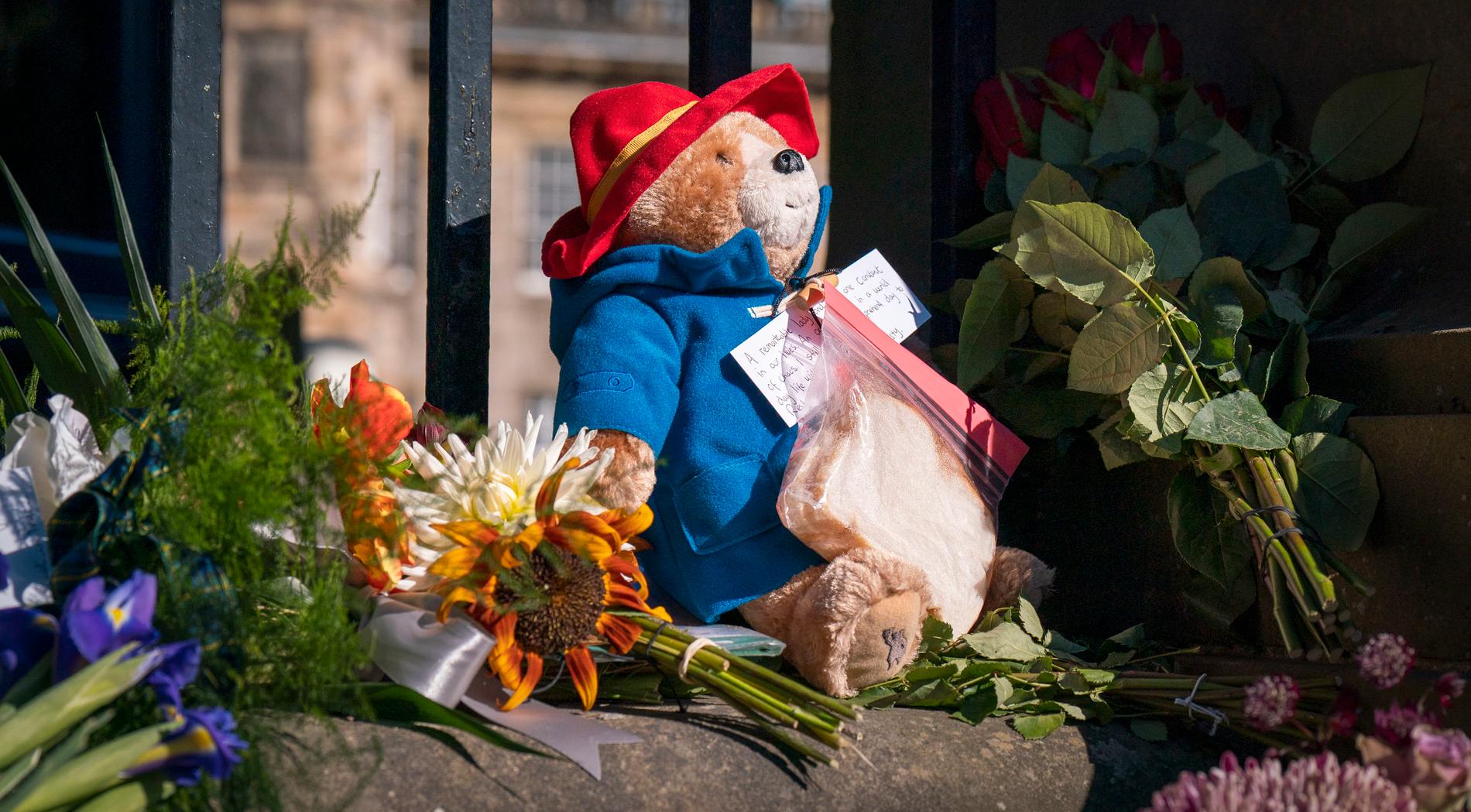 Björnen Paddington och en marmeladsmörgås bland blommor och hyllningar till drottning Elizabeth II.