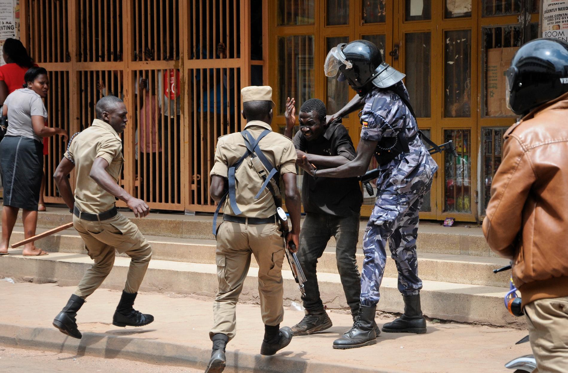 Säkerhetsstyrkor omhändertar en demonstrant i centrala Kampala, där polisen skjutit tårgas mot demonstranterna.