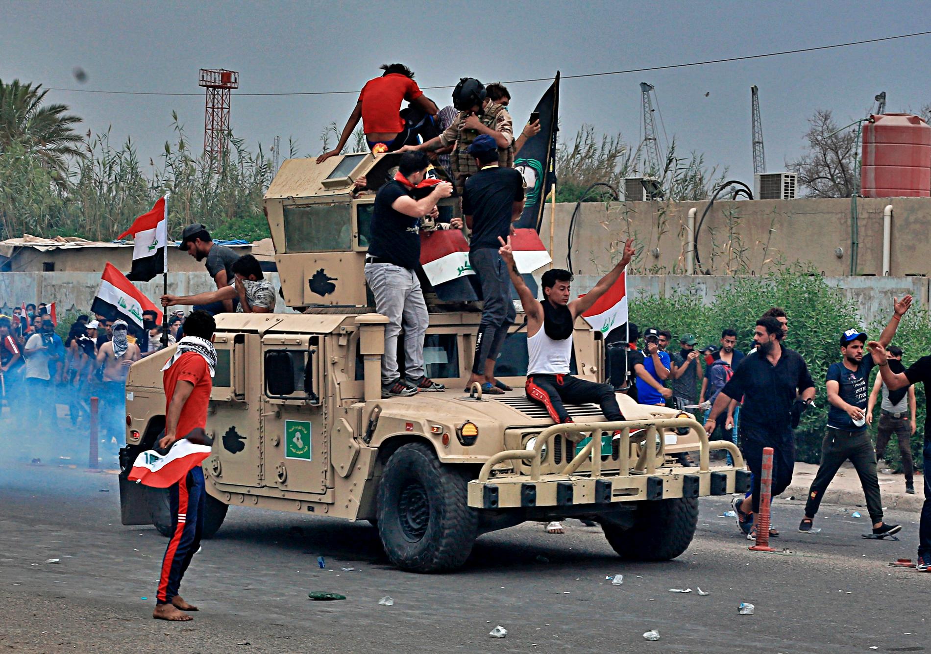 Demonstranter har klättrat upp på ett arméfordon vid demonstrationer i Basra, i södra Irak.
