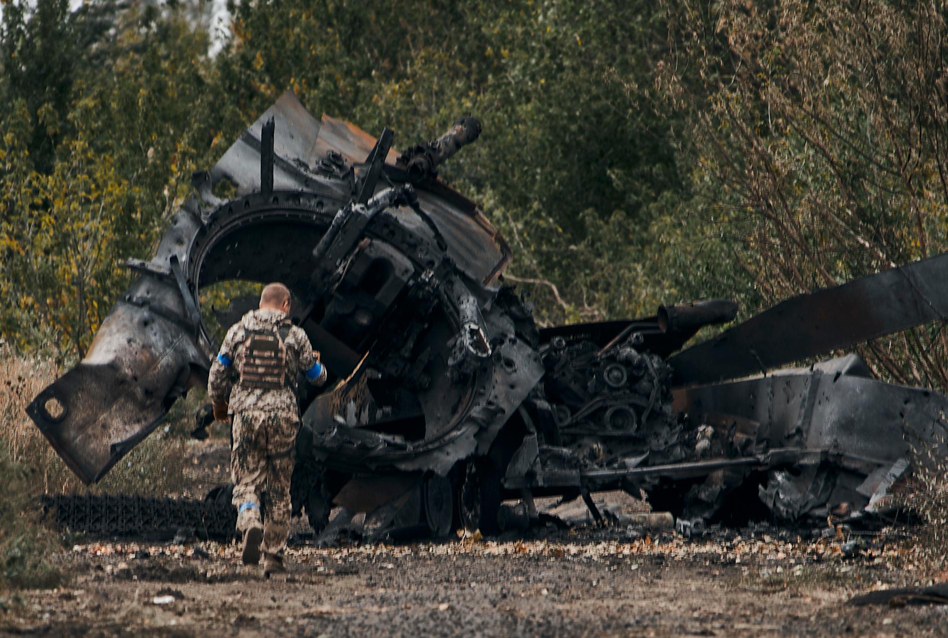 En ukrainsk soldat passerar en sönderskjuten rysk stridsvagn i Charkiv-regionen, söndagen den 11 september.