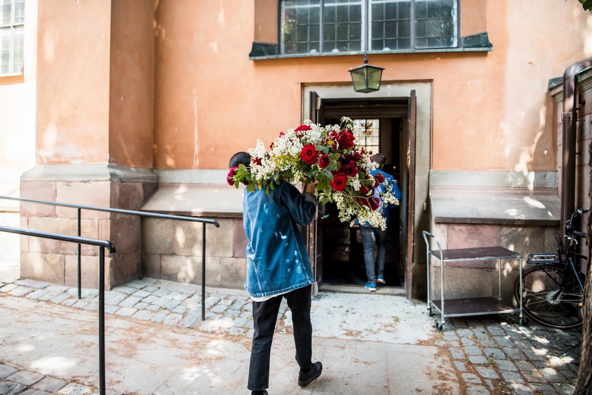Blomsterarrangemang bärs in i Storkyrkan i Stockholm.