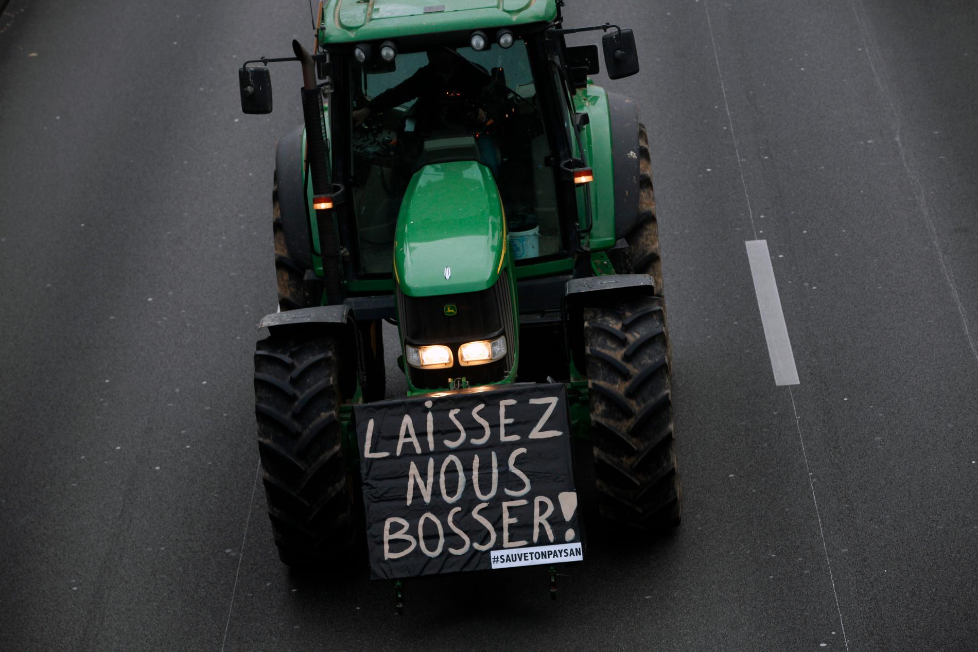 "Låt oss jobba" står det på en av traktorerna som kör på ringvägen kring Paris.